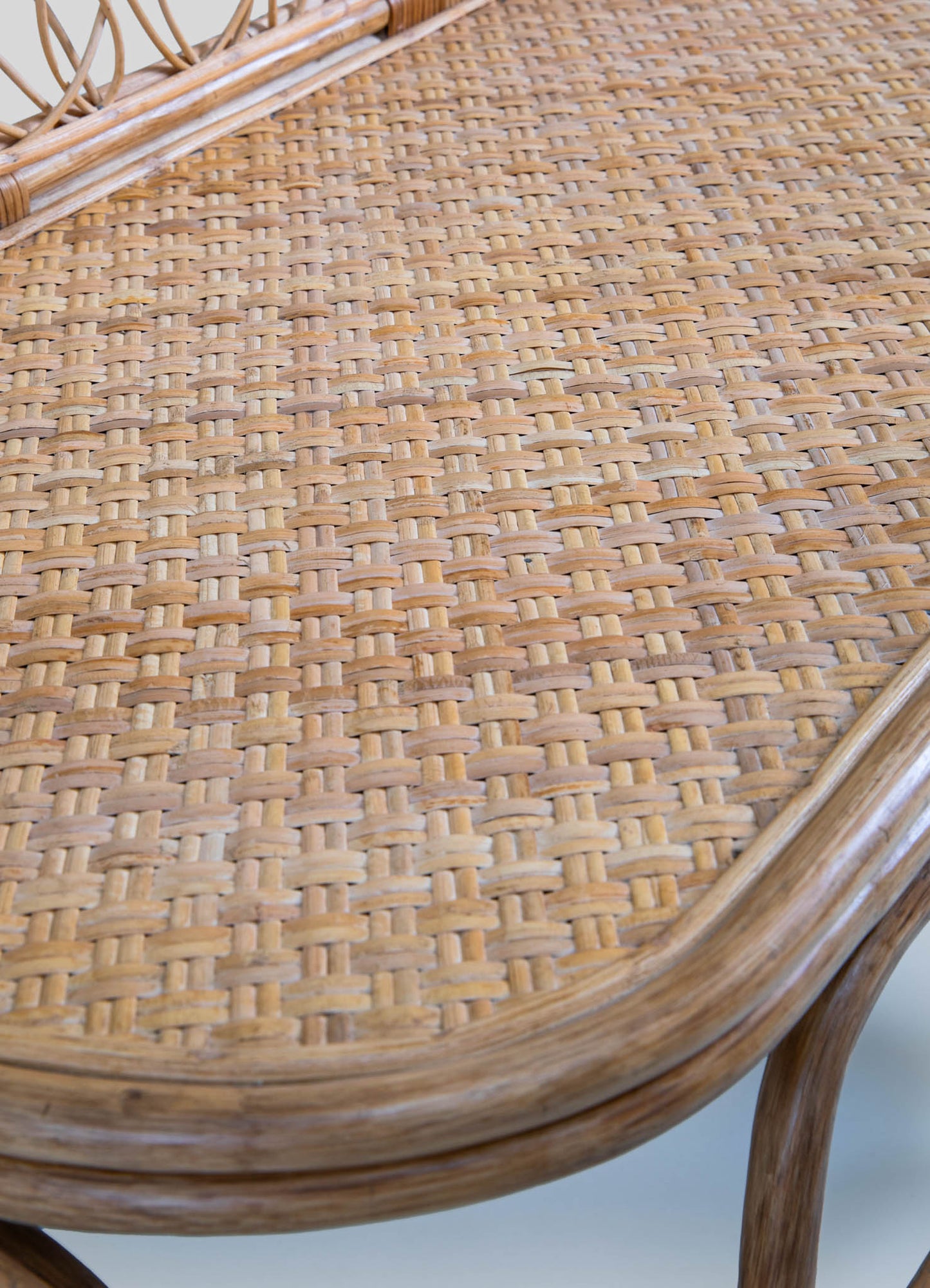 Woven rattan surface with a natural, light beige tone and a subtle textured pattern, framed by curved edges and supported by a matching rattan frame.