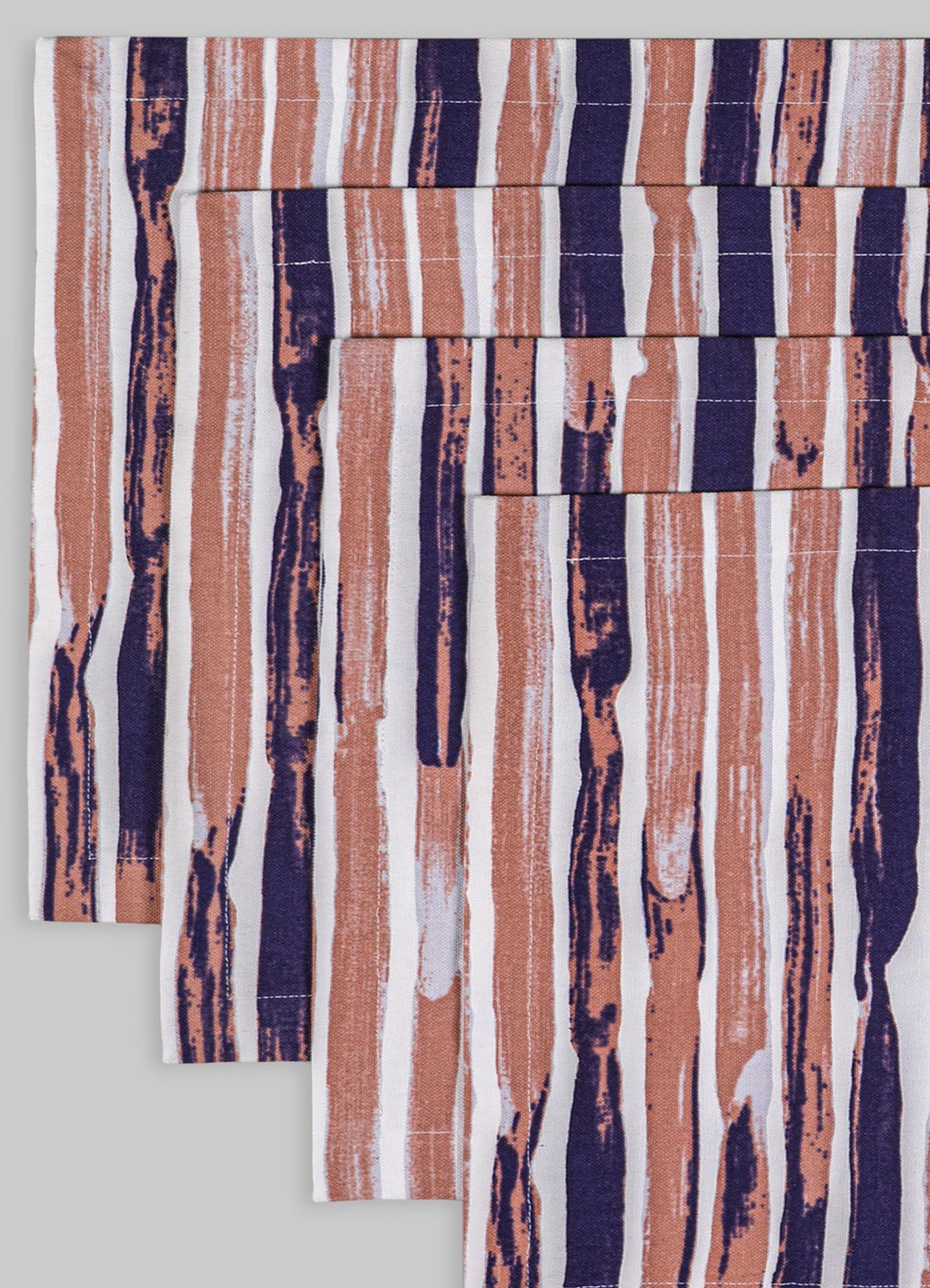 Striped table linen or napkins made of cotton or linen with abstract, painterly lines in shades of beige, navy blue, and white. The fabric features a modern, artistic pattern with a casual, contemporary style.