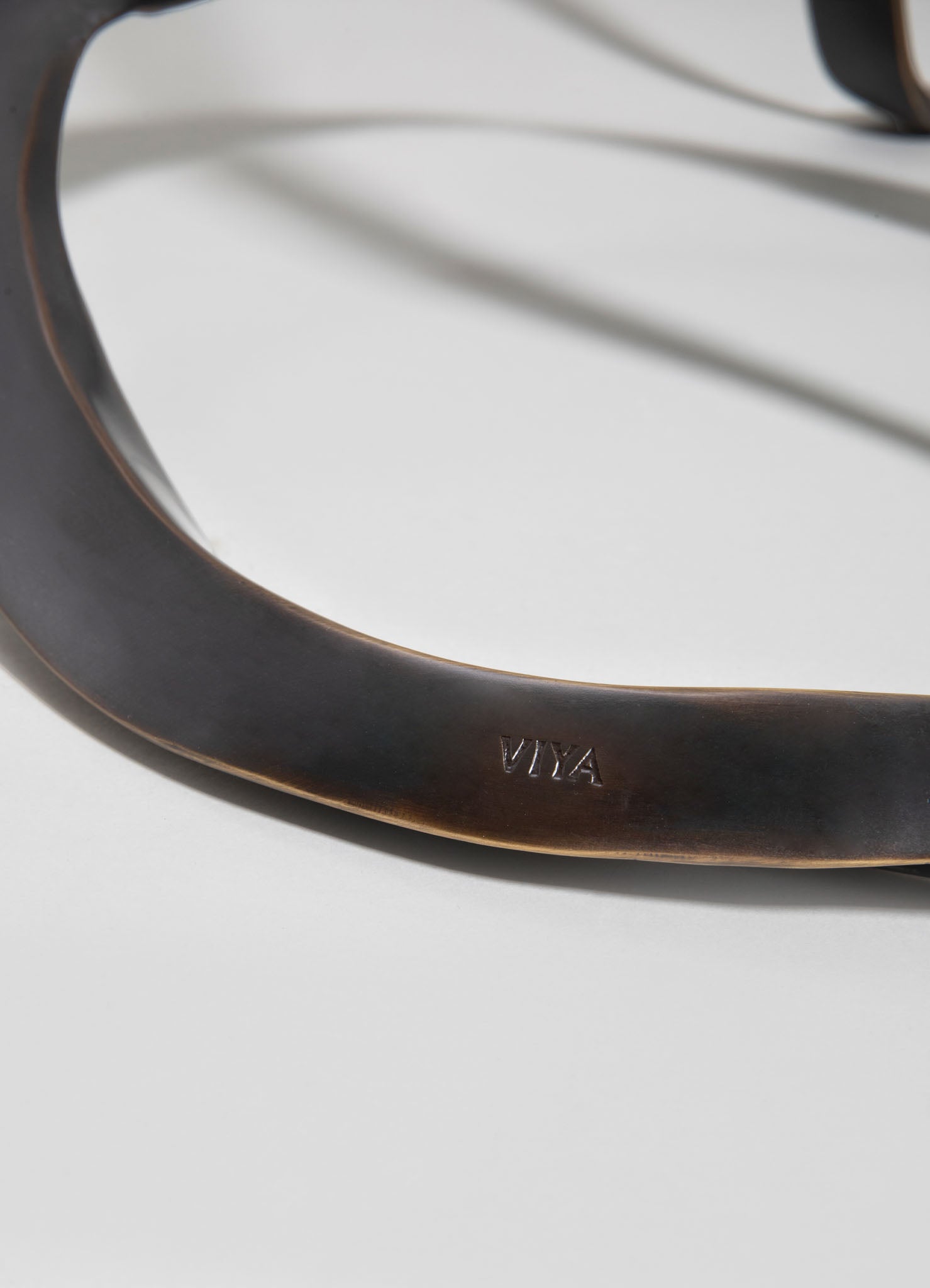 Close-up of a dark wooden or leather item with the engraved word "VIKA", featuring smooth, curved edges and a matte finish. The material appears to be polished and well-crafted, emphasizing quality and craftsmanship.