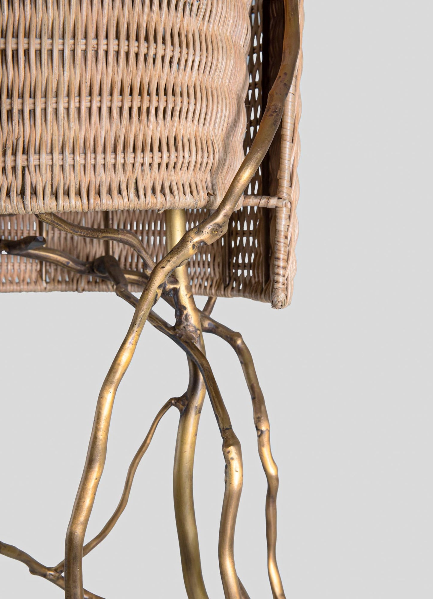 Rattan side table with a woven texture and a natural beige tone, featuring a distinctive golden metal branch-like support structure.