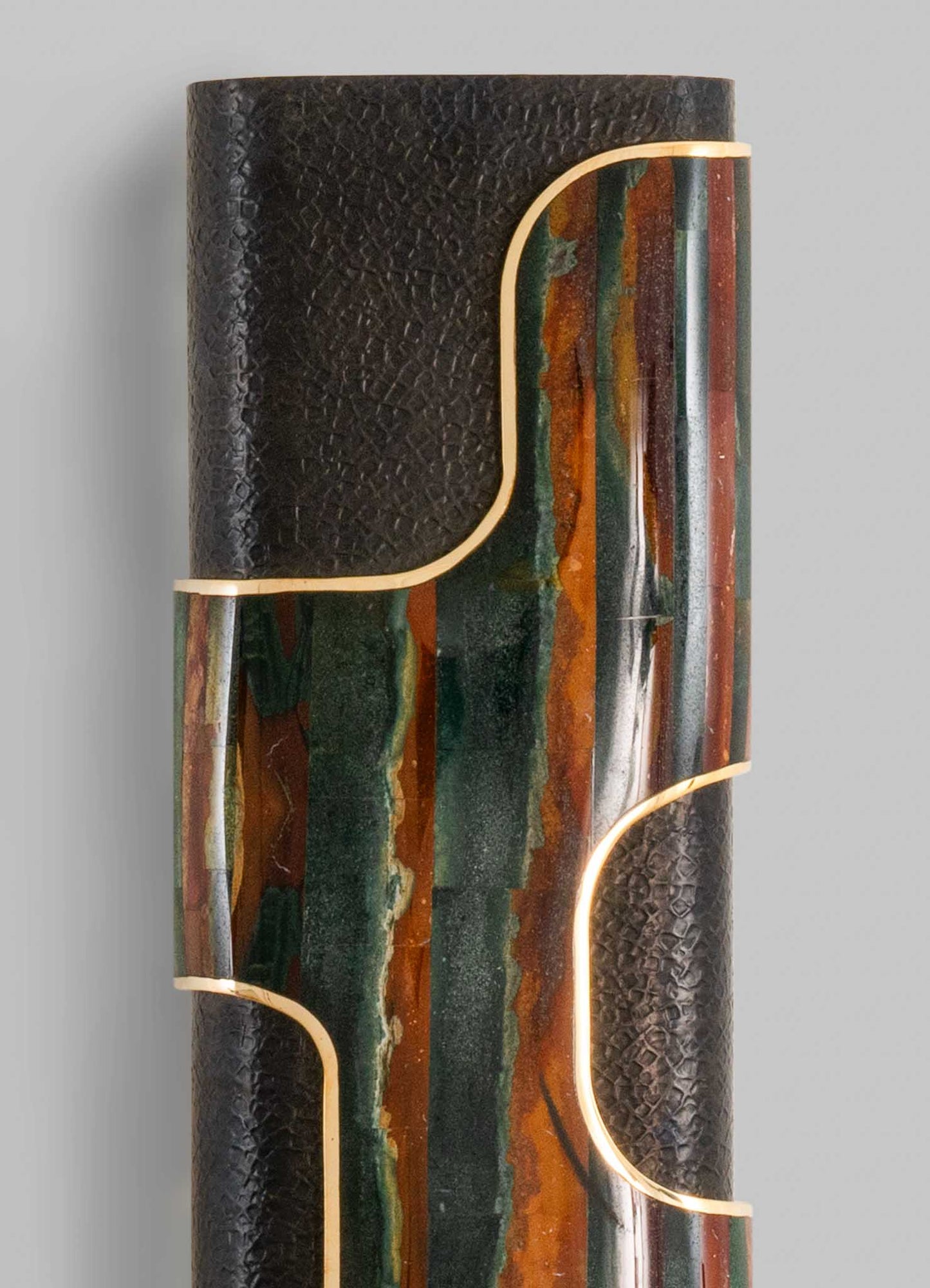 A sculptural table lamp with a textured black surface combined with colorful onyx or marble inlays, featuring gold-toned metallic accents outlining its organic, curvilinear shape.