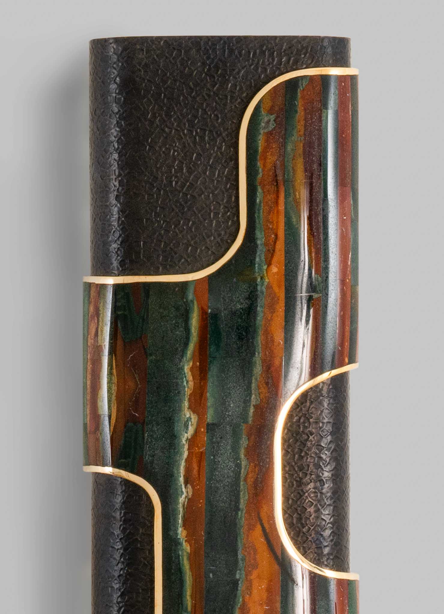 A sculptural table lamp with a textured black surface combined with colorful onyx or marble inlays, featuring gold-toned metallic accents outlining its organic, curvilinear shape.