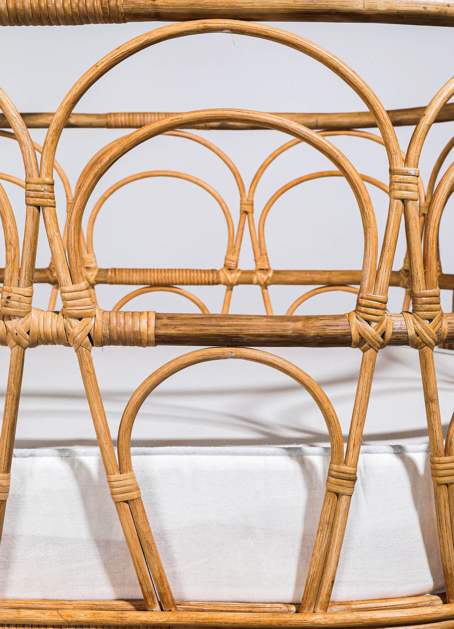 Wicker chair with rounded armrests and intricate weaving patterns, constructed from natural rattan or wicker material in a warm, honey-toned color. The design features curved lines and a handcrafted style, suitable for a rustic or bohemian decor setting.
