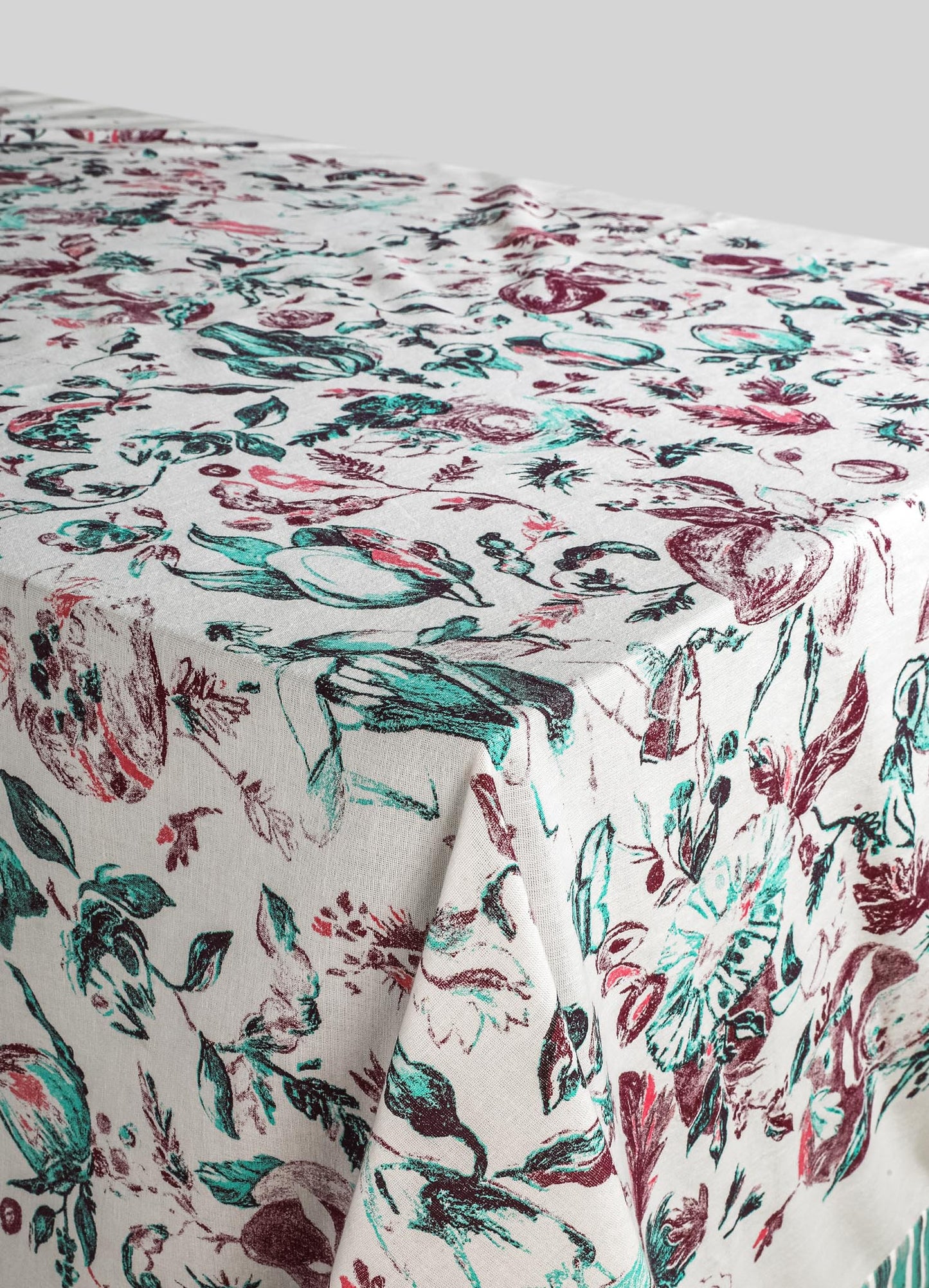 Printed table linen with a floral pattern in shades of red, teal, and black on a white background, made from a lightweight fabric ideal for casual or elegant dining settings.