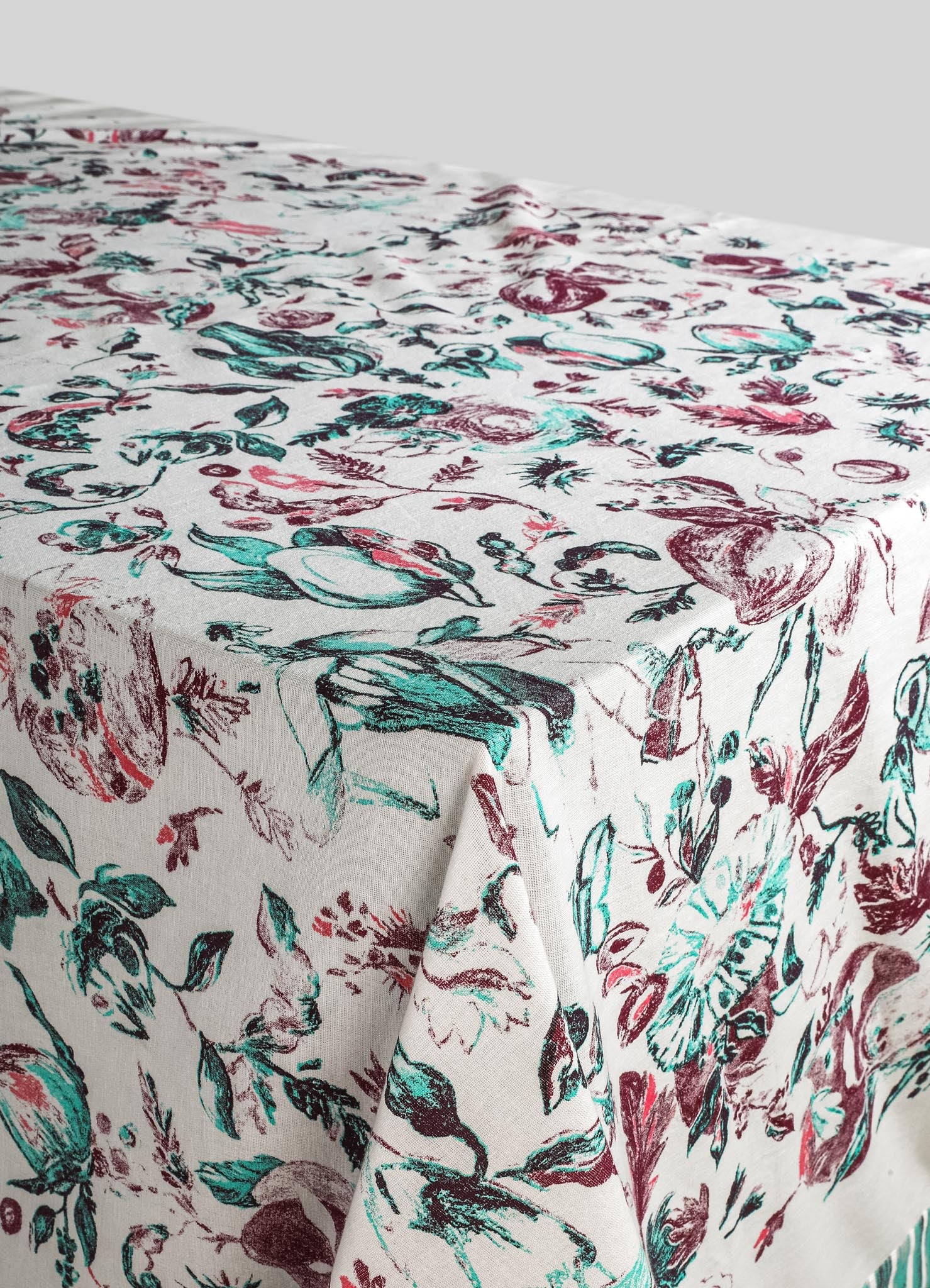 Printed table linen with a floral pattern in shades of red, teal, and black on a white background, made from a lightweight fabric ideal for casual or elegant dining settings.