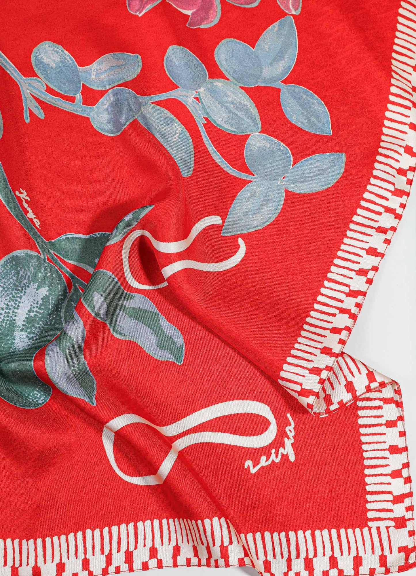 Bright red fabric scarf with a botanical floral motif in pale blue and white, featuring a checkerboard border pattern in white and red. The material appears smooth and lightweight, suitable for accessories or decorative accents.
