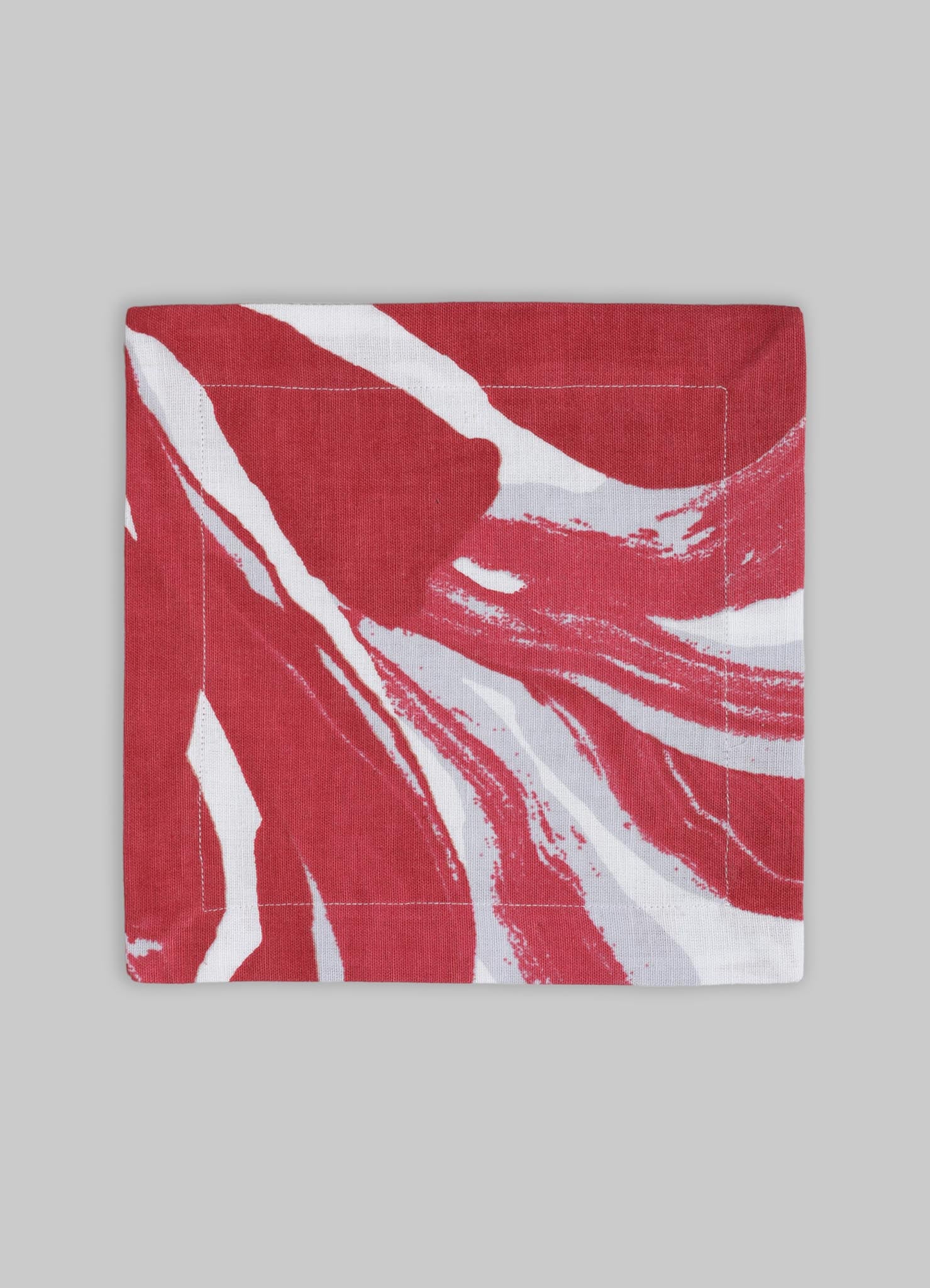 Printed fabric napkin with a red and white abstract pattern, made of cotton or similar material, featuring a contemporary design and bold, organic shapes.