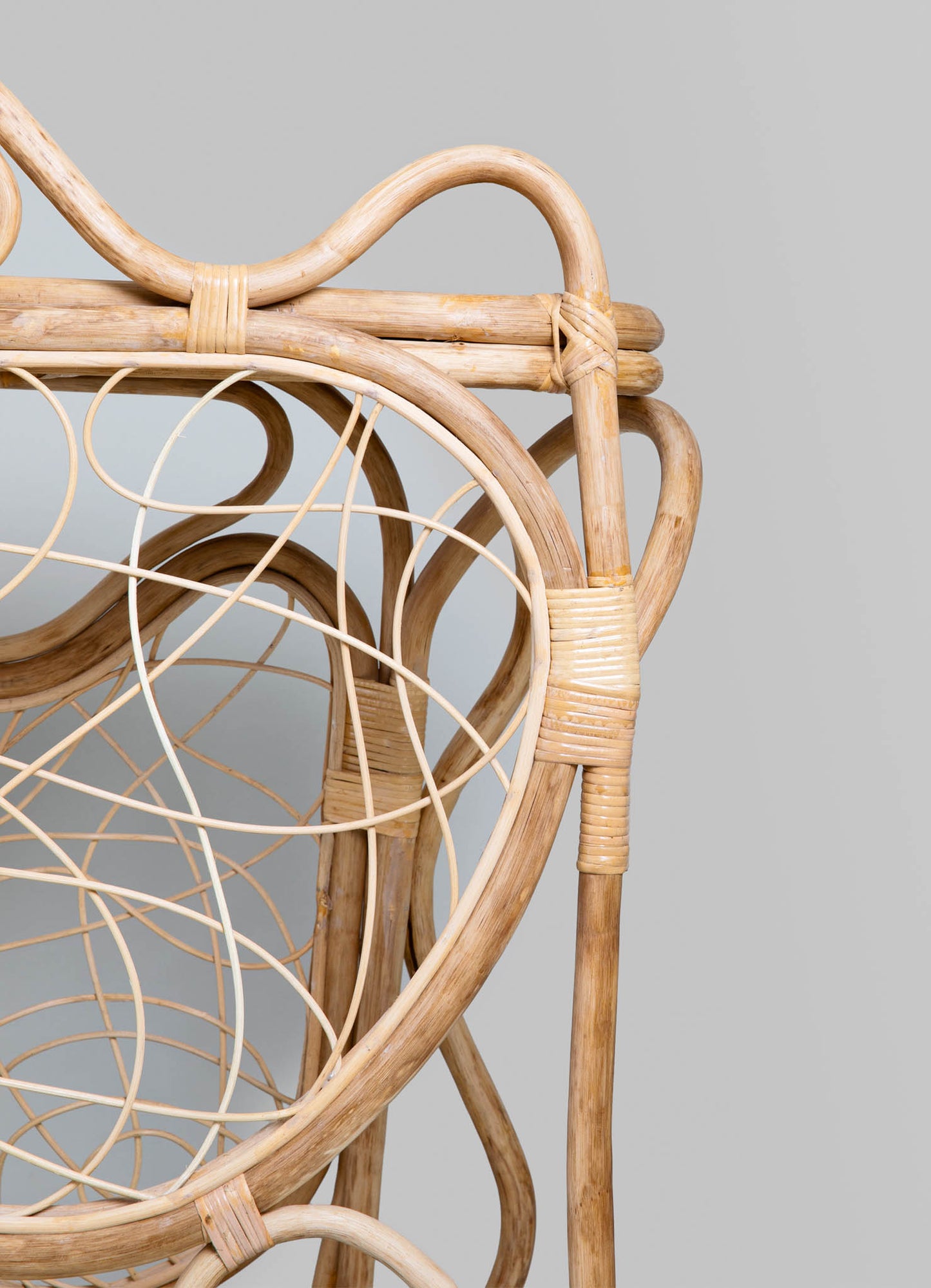 Rattan chair with a natural finish, featuring intricate woven cane seating and a rounded backrest, in a contemporary style with a focus on craftsmanship and organic materials.
