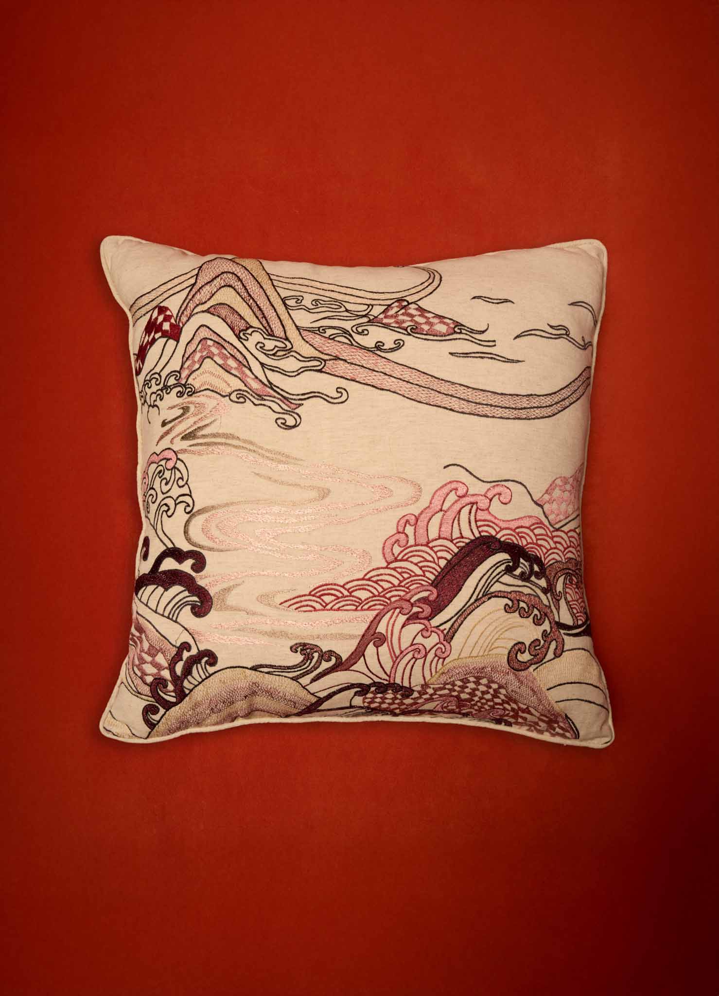 The Viya Dreamscape Red Embroidered Cushion Cover B (24"x24") features abstract wave and swirl embroidery in cream, pink, black, and burgundy on a solid reddish-orange background, inspired by Rajput manuscript art motifs.