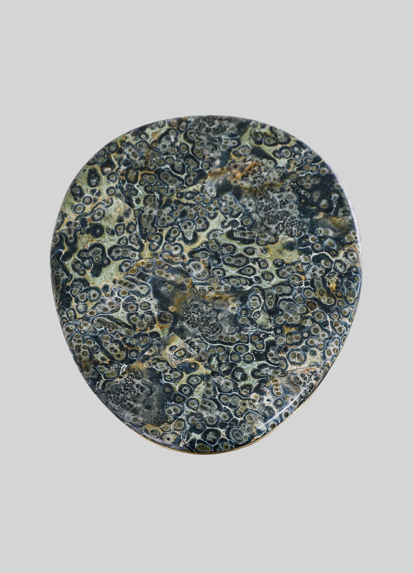A round marble tray with a dark and beige swirling pattern, featuring intricate circular and organic motifs. The surface appears polished with a smooth finish, set against a neutral background.