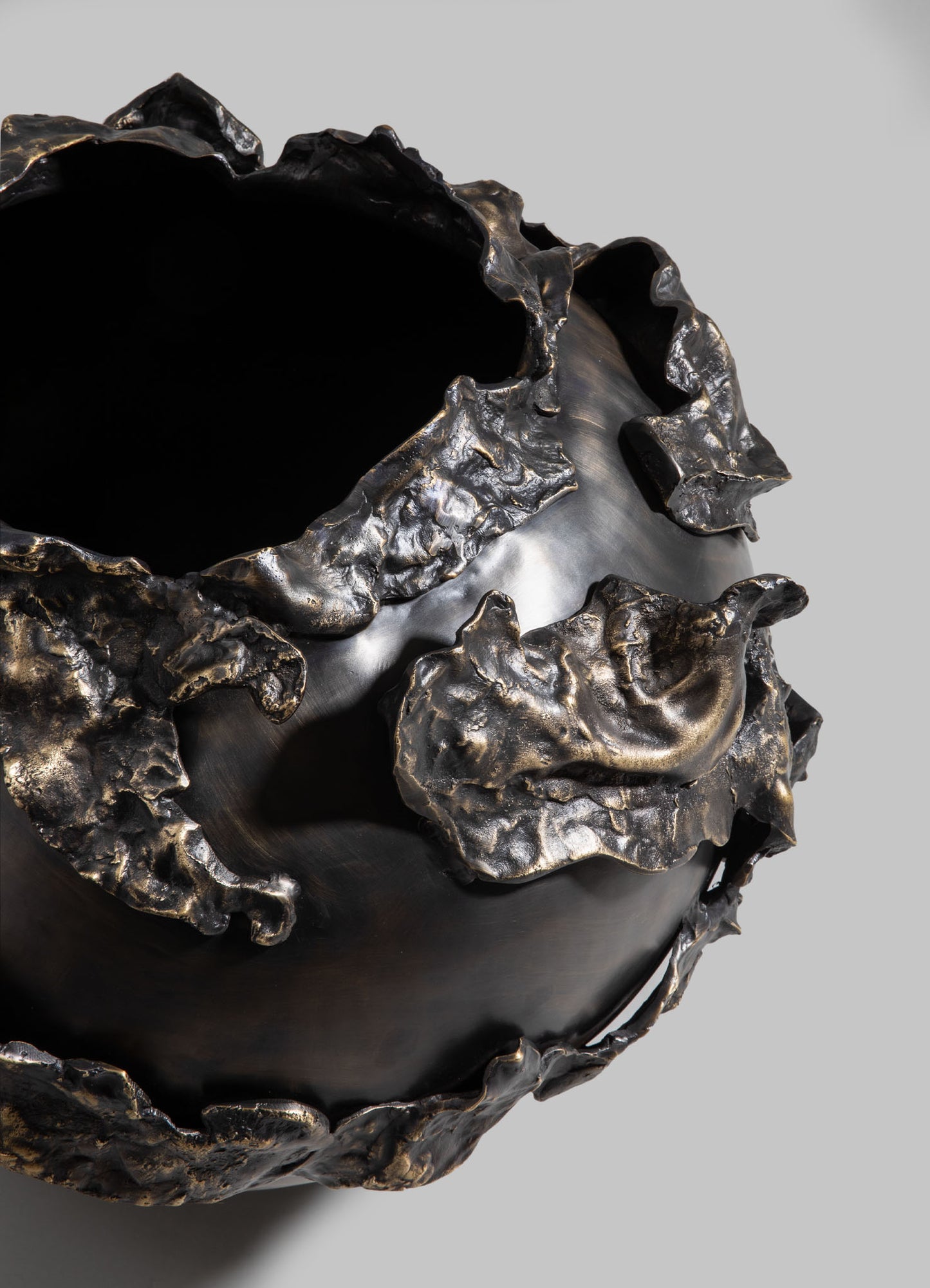 Black ceramic bowl with irregular, textured metallic gold accents on the rim and exterior, featuring a glossy finish and organic, uneven shapes.