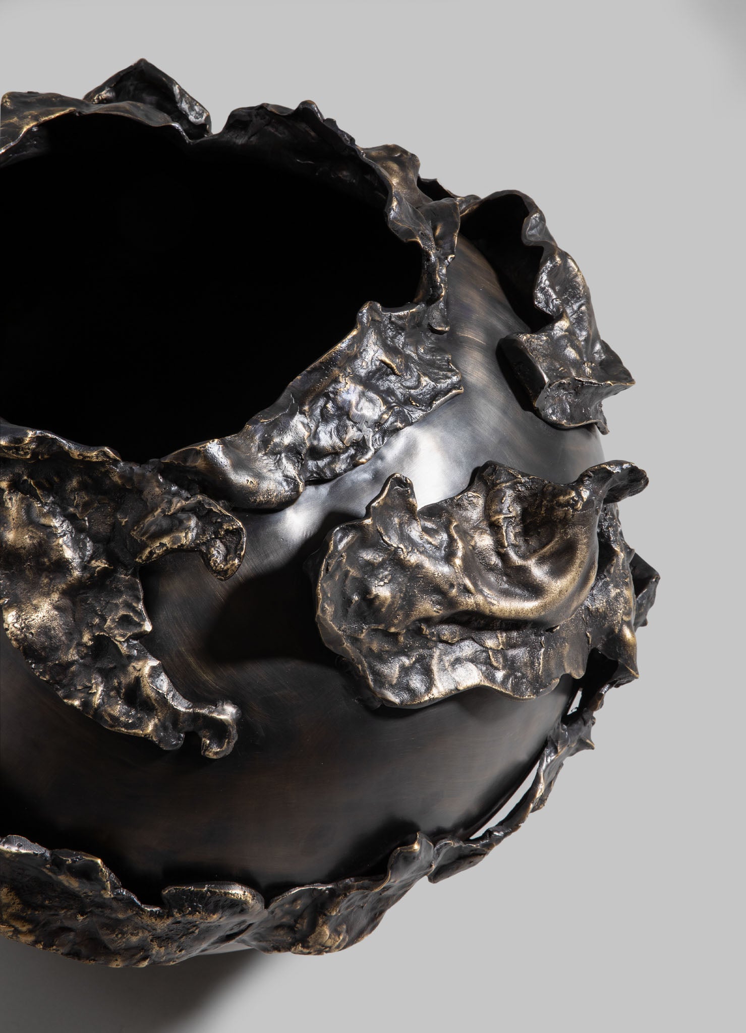 Black ceramic bowl with irregular, textured metallic gold accents on the rim and exterior, featuring a glossy finish and organic, uneven shapes.