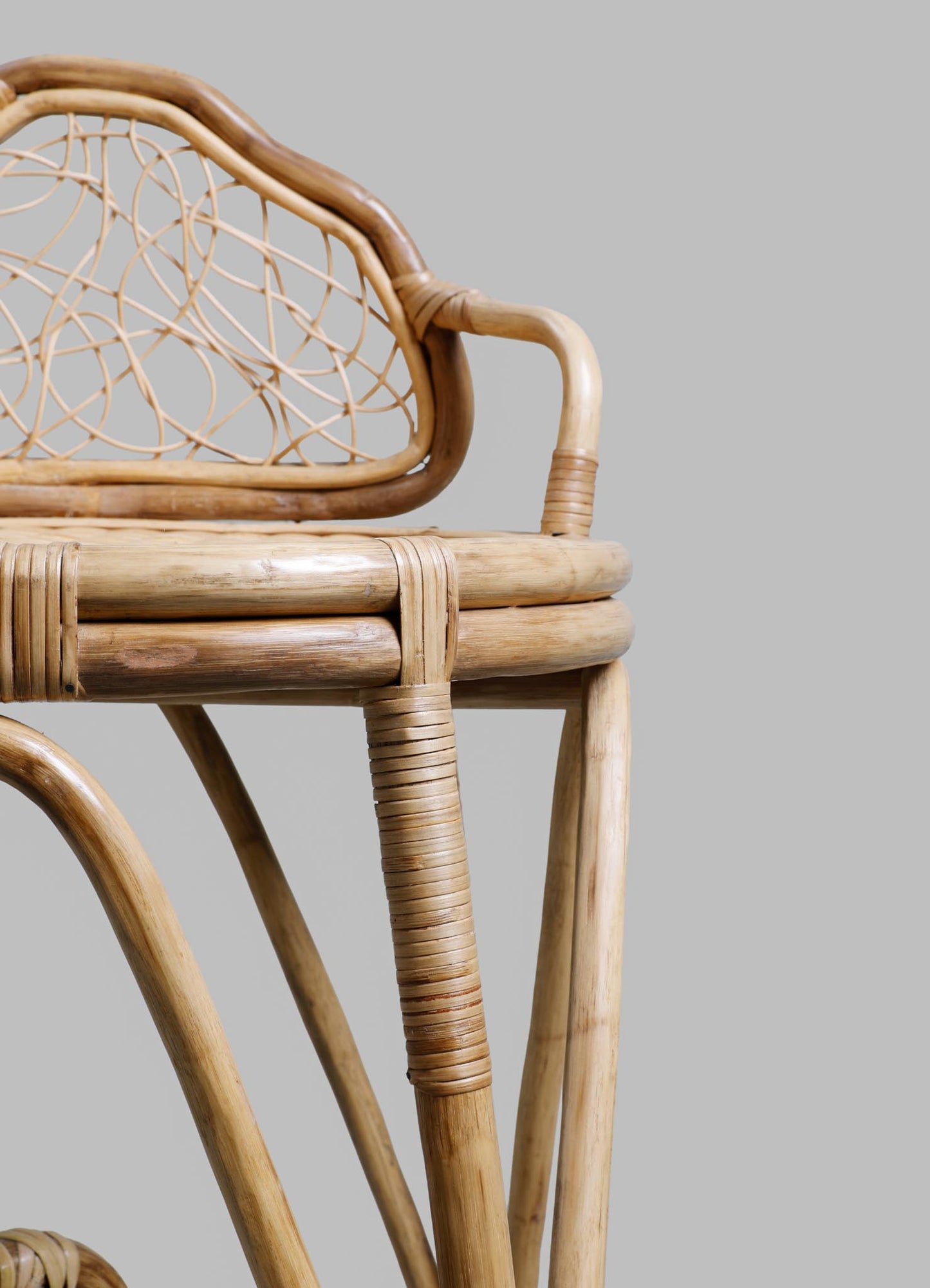 Rattan armchair with a woven cane backrest featuring a geometric pattern, light natural wood finish, and rounded armrests.