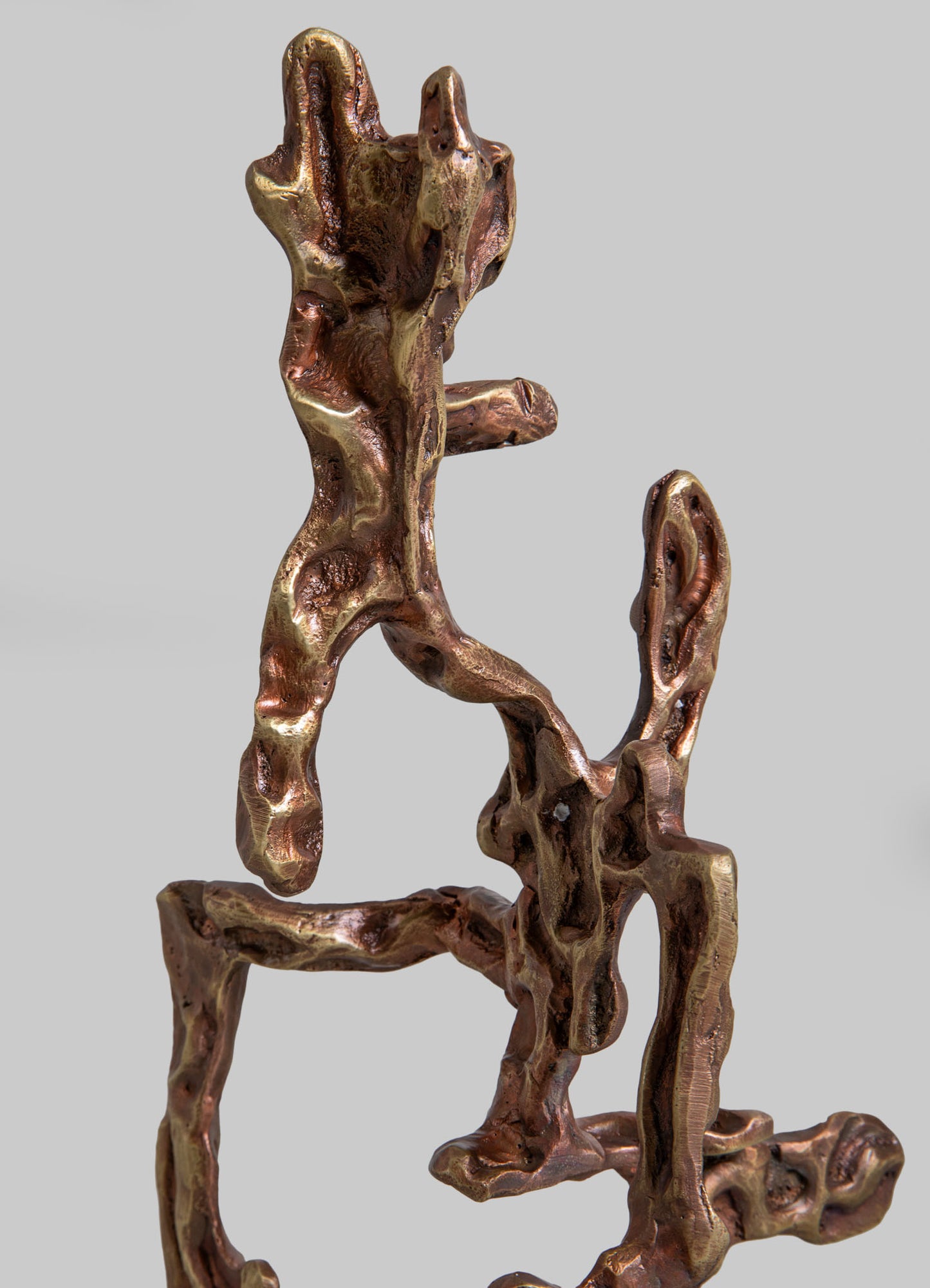 Bronze sculpture with an abstract, organic form featuring twisted, interconnected shapes and a polished, metallic finish. The artwork has a contemporary, handcrafted style with a warm, reddish-golden tone.