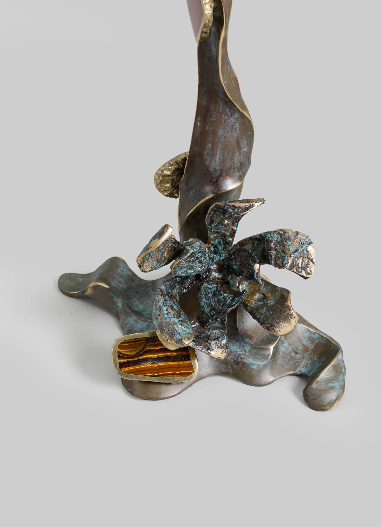 Decorative sculpture with a rustic, handcrafted style featuring abstract, organic forms in bronze and patina finishes, including a pop of tiger's eye gemstone at the base.