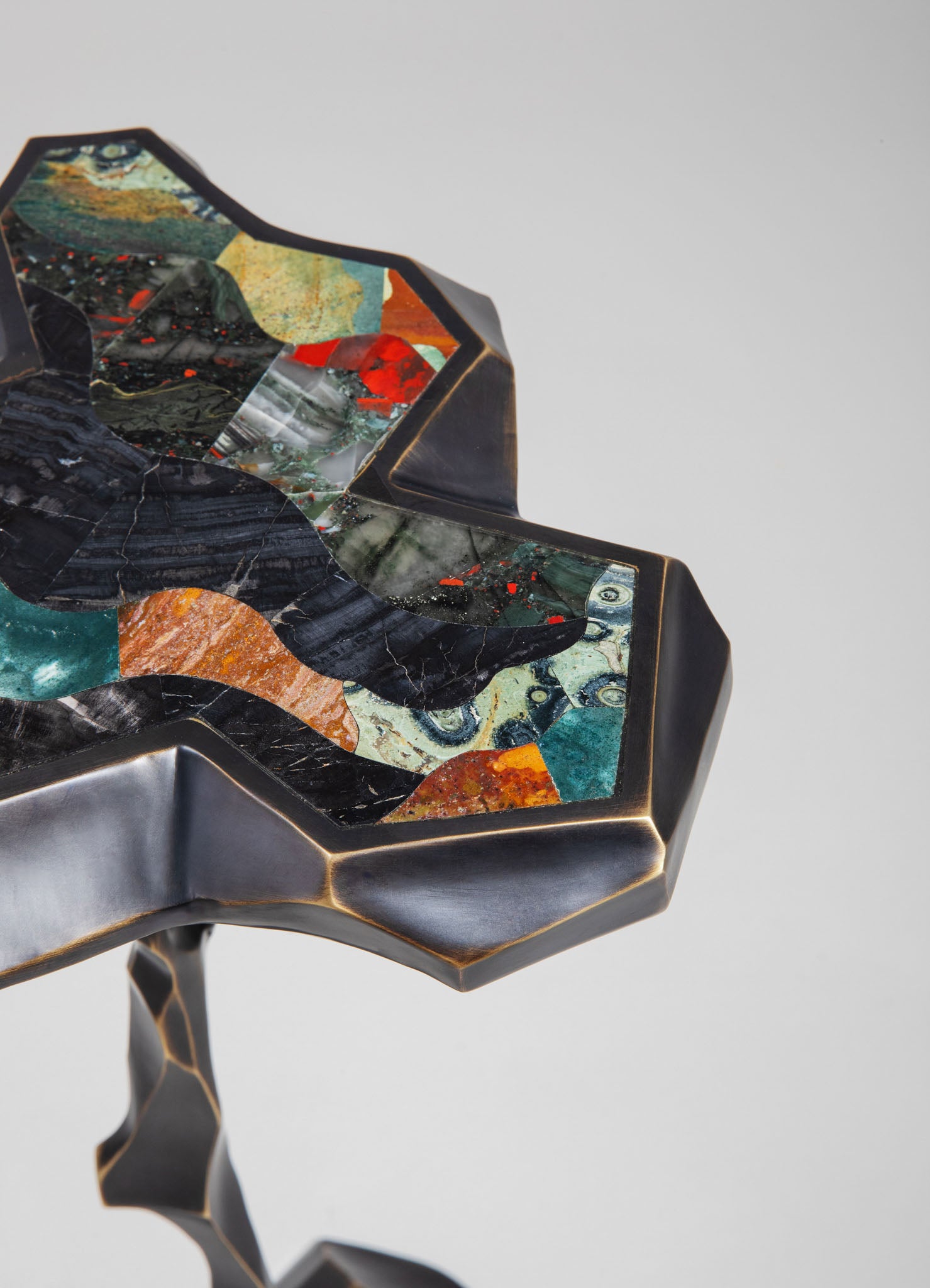 Decorative side table with a geometric metal frame finished in matte black and a colorful, abstract resin inlay featuring swirling patterns and vibrant hues.