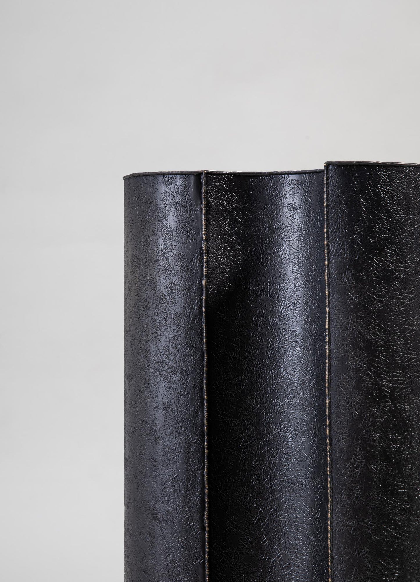 A textured black leather cushion with a subtle pebbled pattern, featuring visible topstitching along the edges. The cushion appears to be rectangular and has a contemporary style.