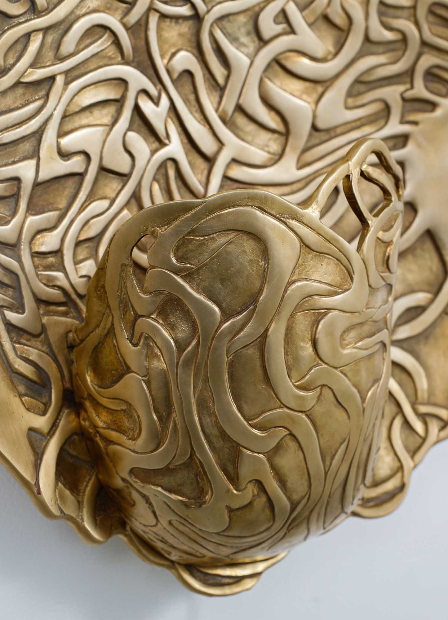 Decorative brass sculpture with intricate, flowing lines and a layered, textured surface, featuring a combination of matte and polished gold tones. The piece has an abstract, organic form that emphasizes craftsmanship and elegant design.
