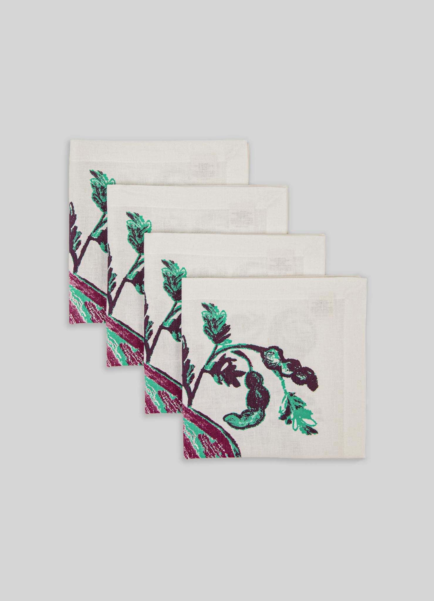 Set of four linen napkins with embroidered botanical motifs in green and purple on a white background, featuring a simple hemstitch edging for a clean finish.