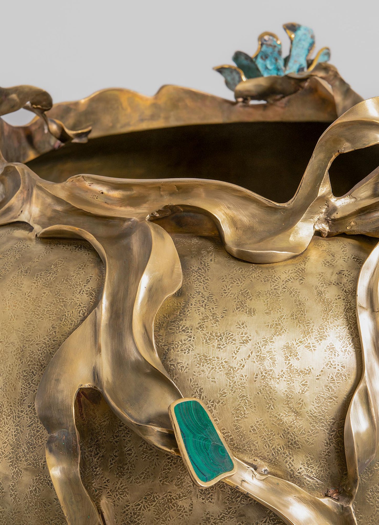 Decorative metal bowl with floral motif and textured gold surface, accented by a turquoise stone in a rustic style.