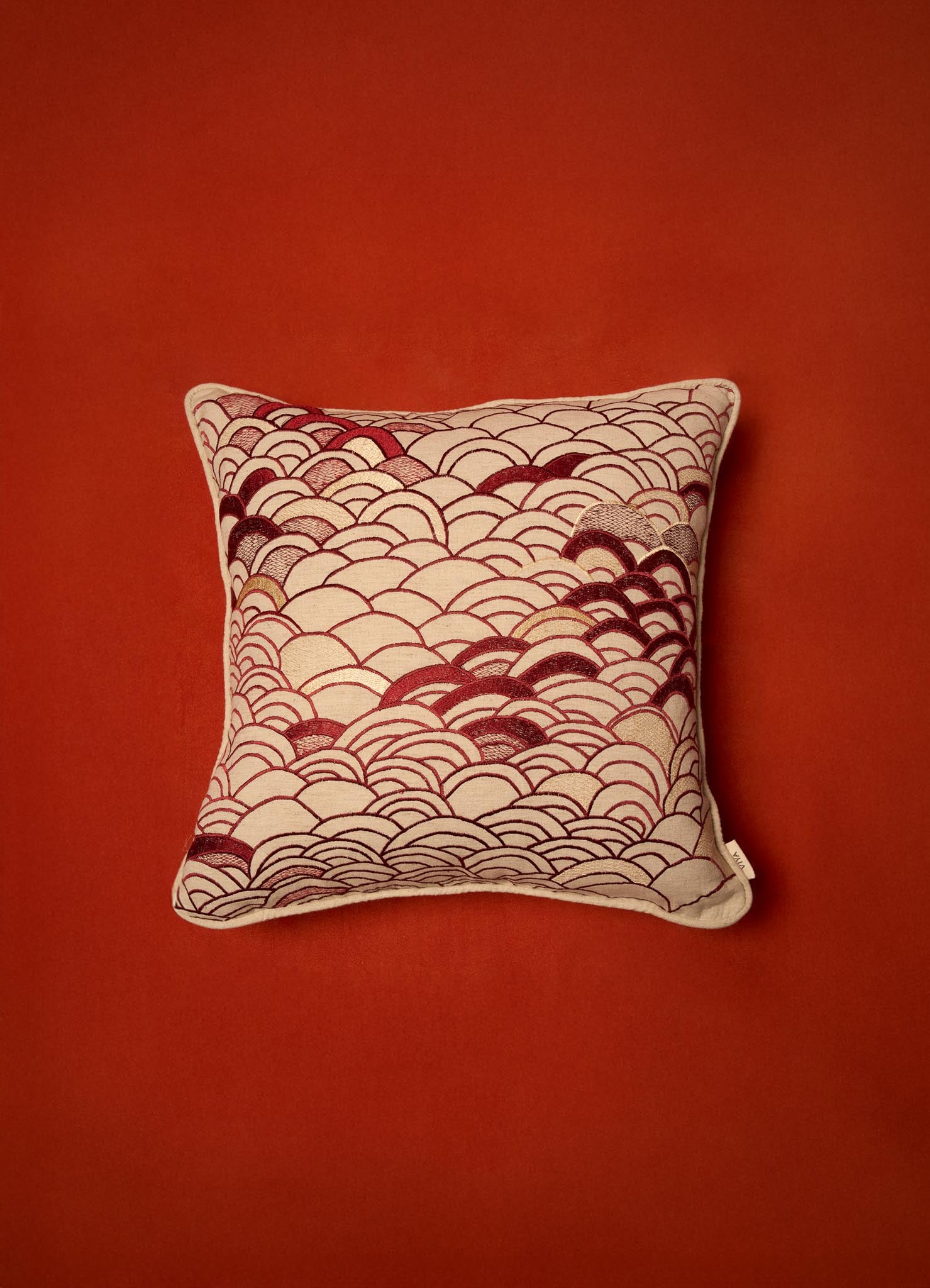 The Viya Dreamscape Red Embroidered Cushion Cover B (18"x18") features a cream base with overlapping red and dark red scallop patterns, inspired by embroidered textiles, perfect for a rust-colored background.