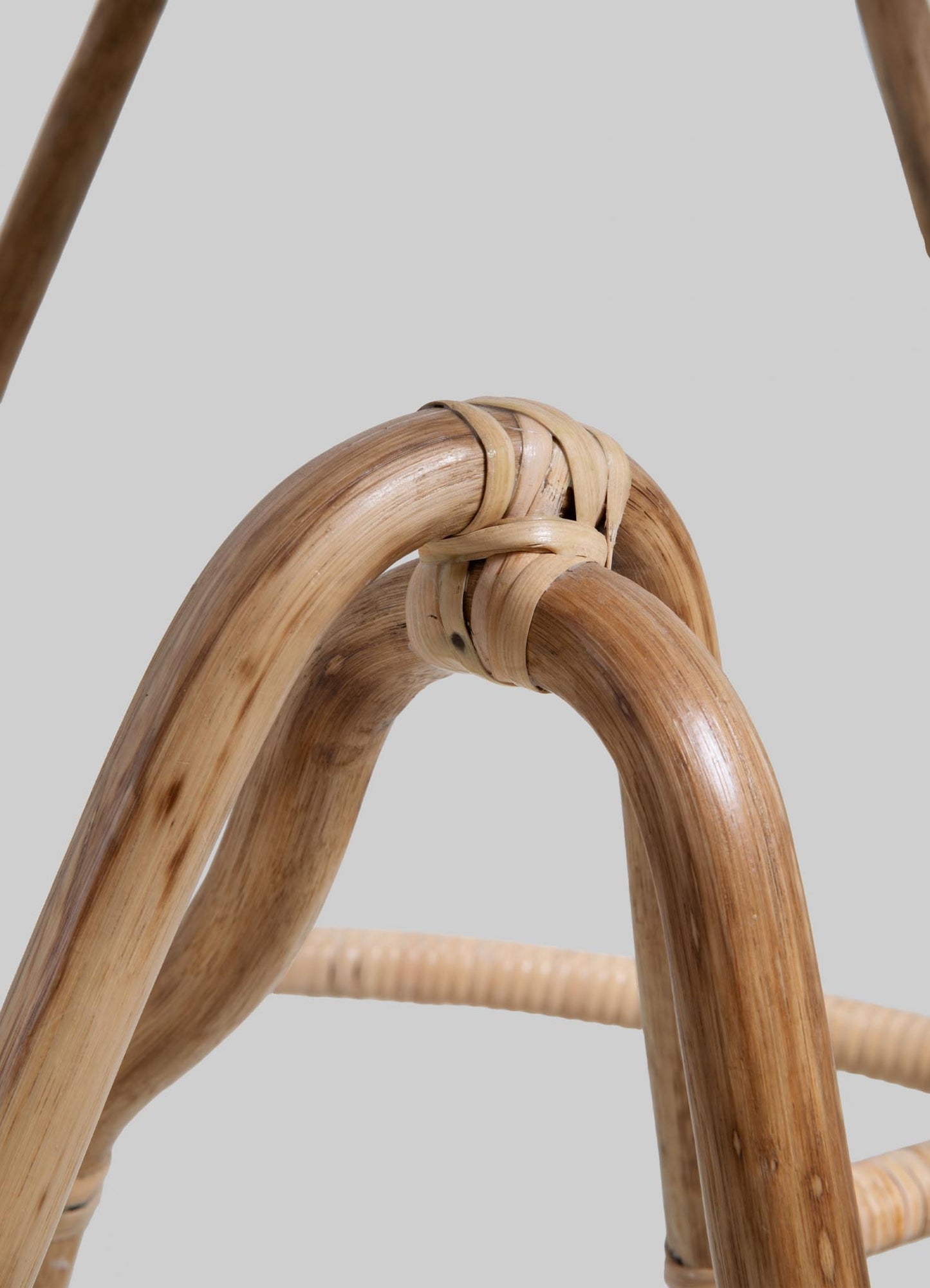 Rattan chair frame with curved wooden arms and woven rattan details, featuring a natural finish and smooth, rounded edges.