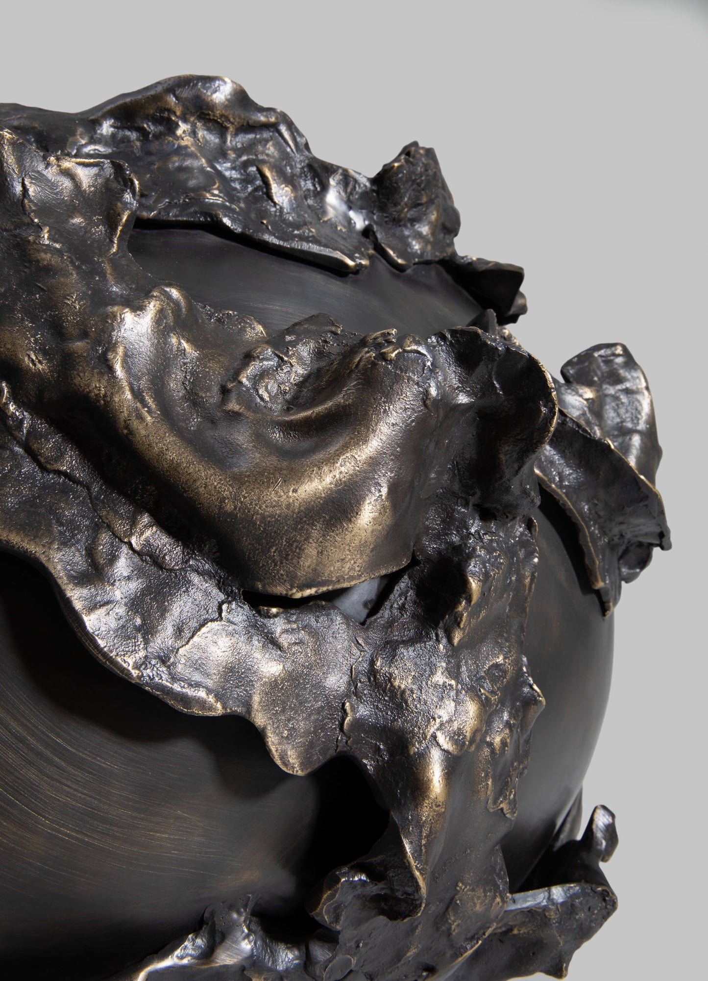 A decorative sculpture with a matte black finish featuring flowing, organic shapes with textured, metallic accents in bronze tones. The piece has a contemporary, abstract style with an emphasis on fluidity and form.