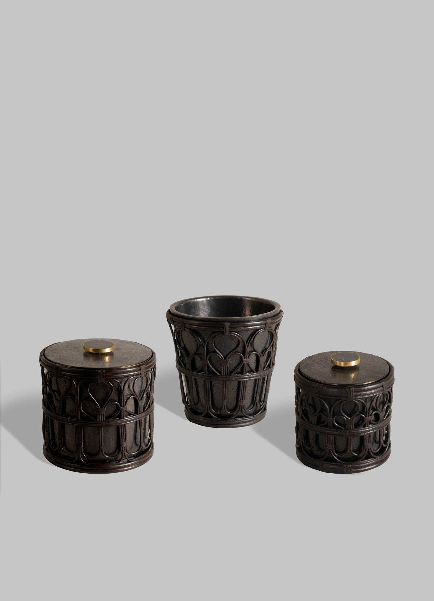 Three intricately carved black Manipur Ice Bucket Small containers by VIYA, each with hand-beaten brass knobs, are displayed on a plain grey background; the open, slightly taller middle container is ideal for classic barware accessories.