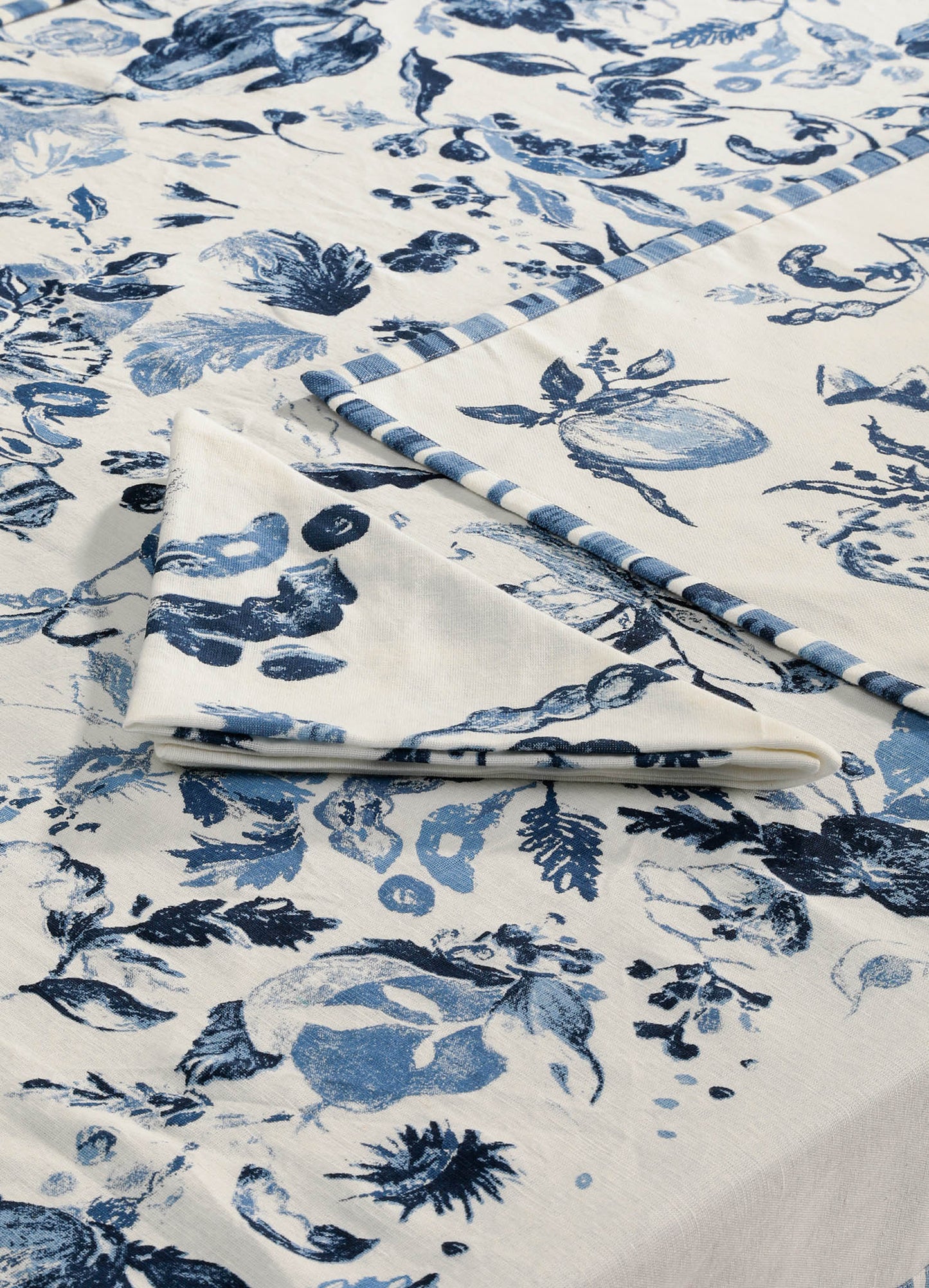 Printed fabric with a floral motif in shades of blue on a cream background, featuring a washed or watercolor effect, suitable for home textiles or apparel. The material appears to be lightweight and soft, with a clean, modern design style.