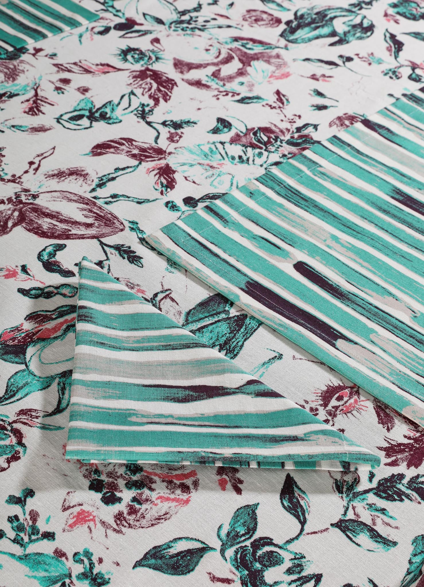 Fabric with a floral and striped pattern, featuring botanical motifs in teal, burgundy, and black on a white background. The material appears to be cotton or linen, with a mix of printed floral designs and horizontal striped accents.