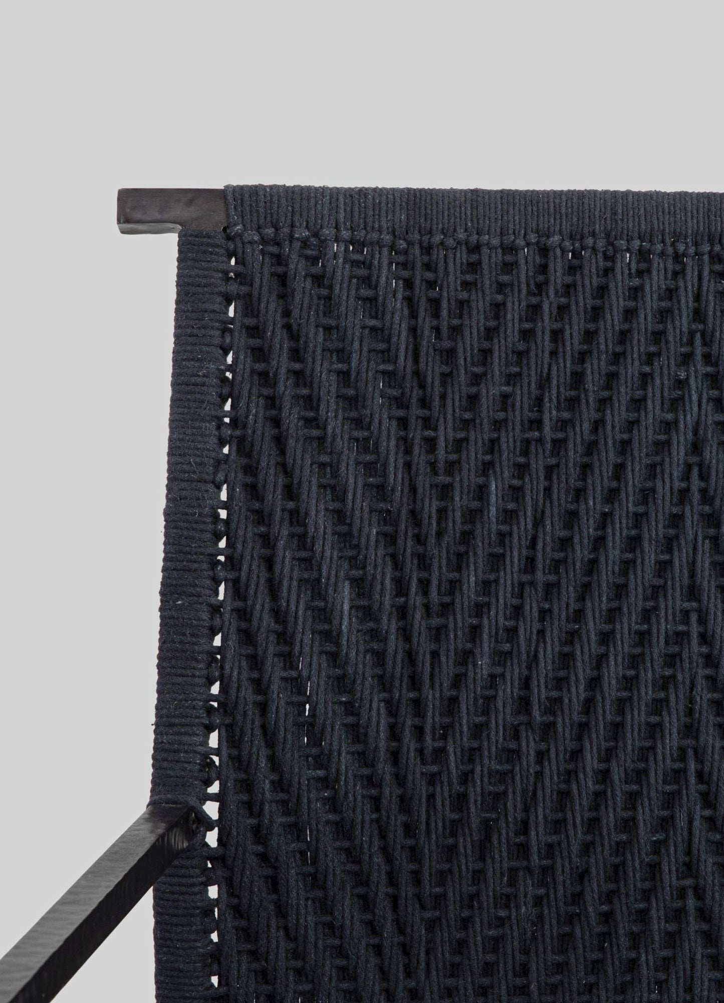Wicker side table or accent piece with a woven pattern in dark navy or black tones, featuring a sturdy black metal frame and top edge, in a contemporary style.