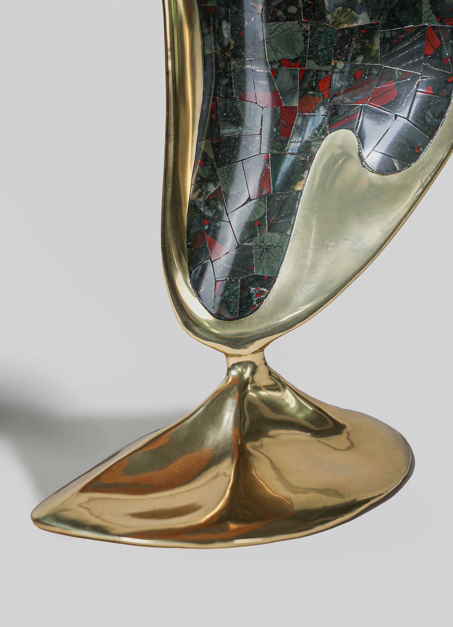 A decorative vessel with a gold-plated metal frame and a mosaic pattern of dark green, red, and black tiles, featuring a glossy finish and organic, flowing form.