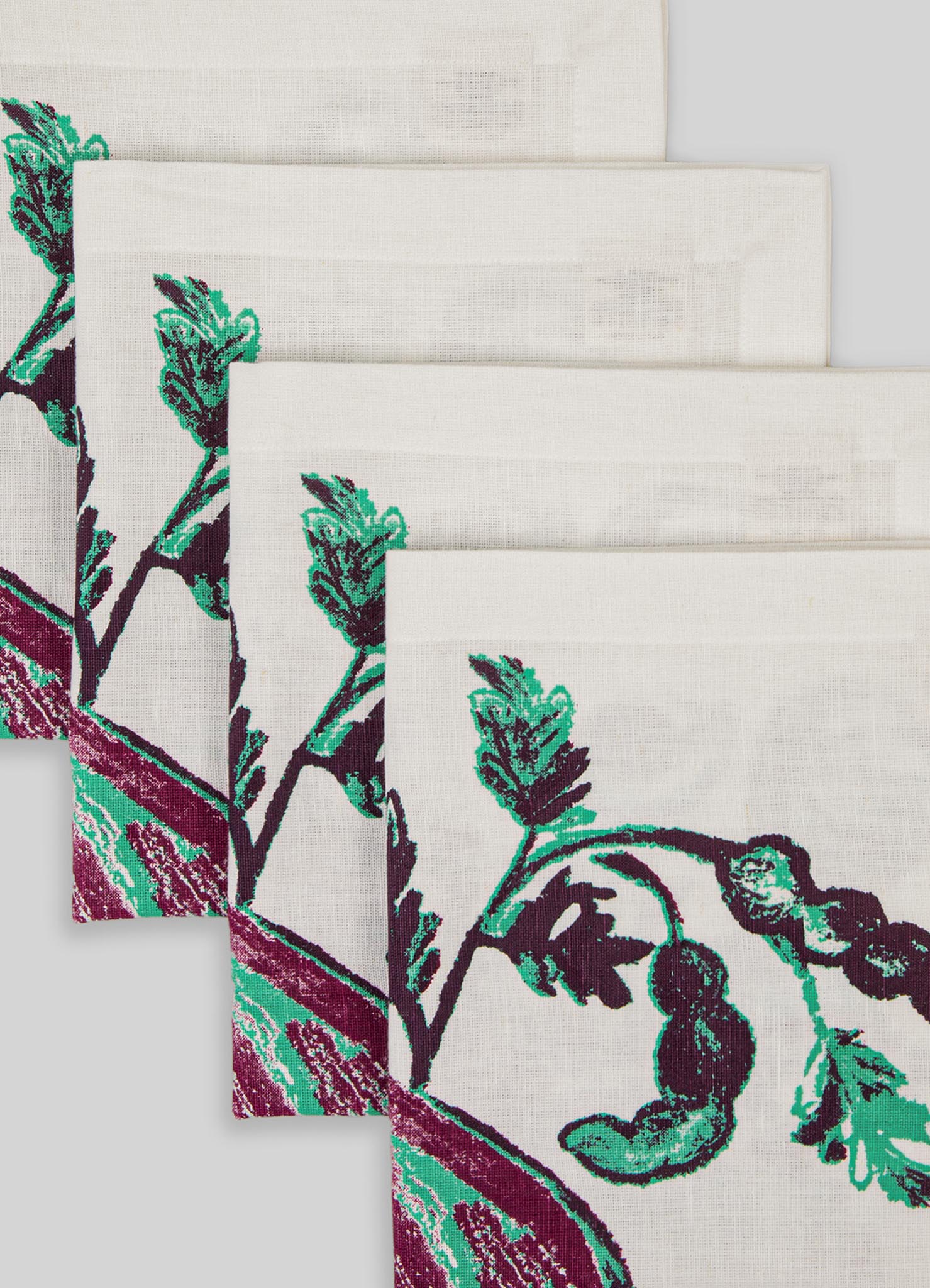 Patterned linen or cotton napkins with a botanical motif in shades of teal, purple, and white, featuring large leaf and stem designs. The fabric appears to have a textured weave and contrasting borders, suitable for table linen.