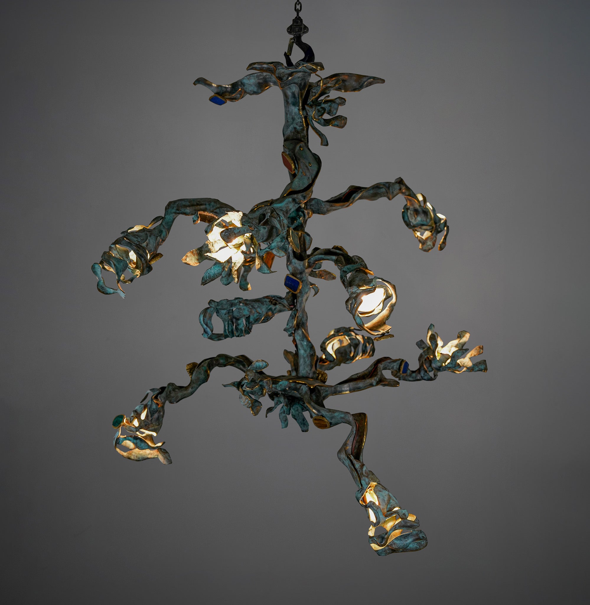 A sculptural ceiling light fixture crafted from metal with an abstract, organic form and a combination of bronze and oxidized patina finishes, featuring integrated light bulbs.