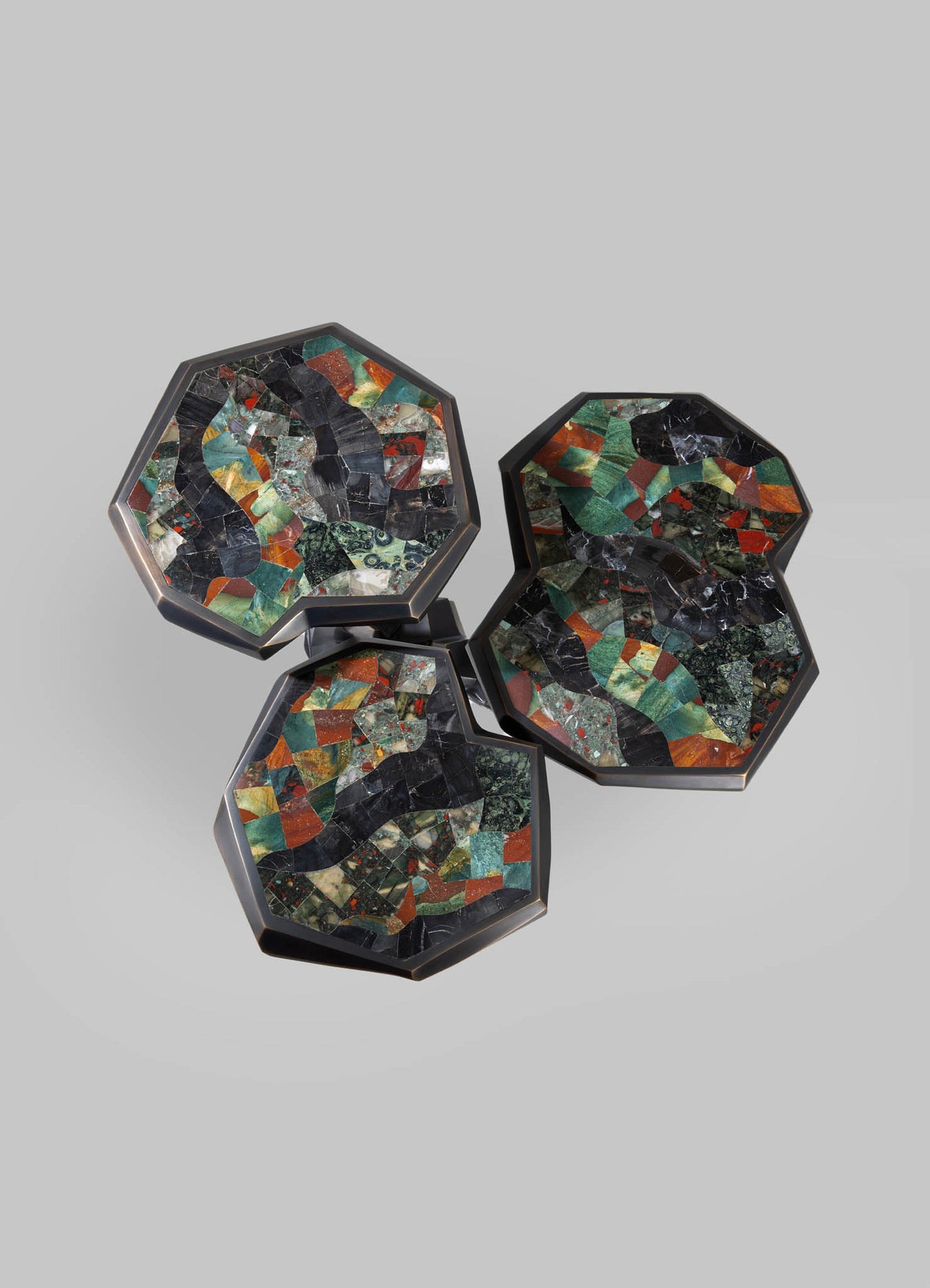 Triangular-shaped marble coasters with geometric motifs in green, black, red, and white tones, set in black metal frames on a neutral background.