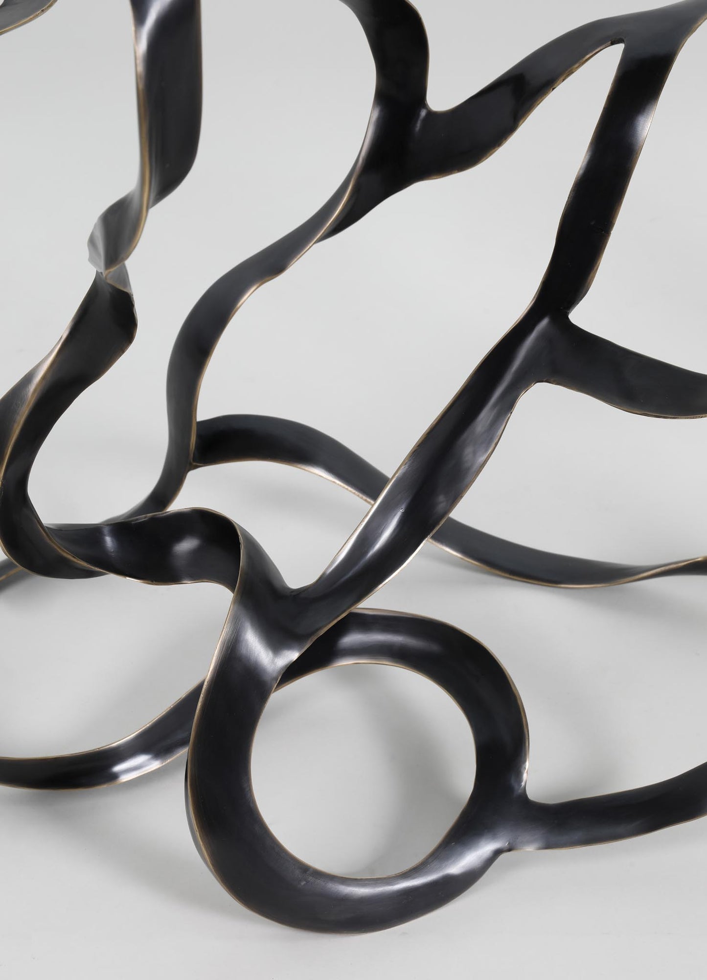 Abstract sculptural piece made of black metal with organic, flowing shapes and a matte finish.