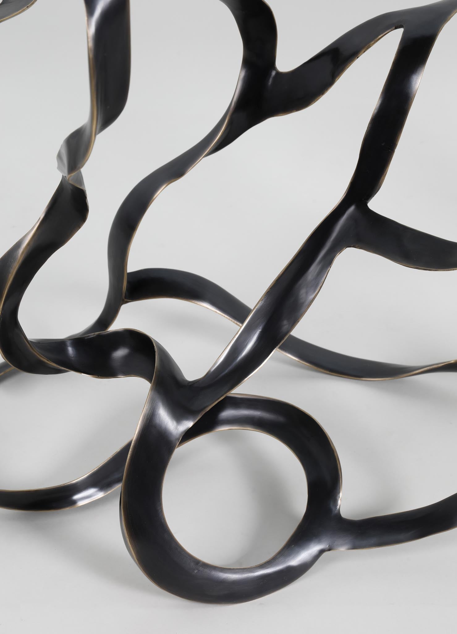 Abstract sculptural piece made of black metal with organic, flowing shapes and a matte finish.