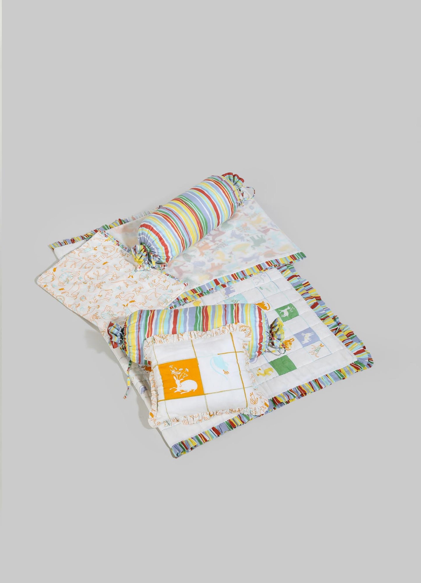 Children's bedding set with animal and floral prints, including a quilt, pillowcases, and a cylindrical bolster, made of cotton fabric with colorful striped and patterned designs.