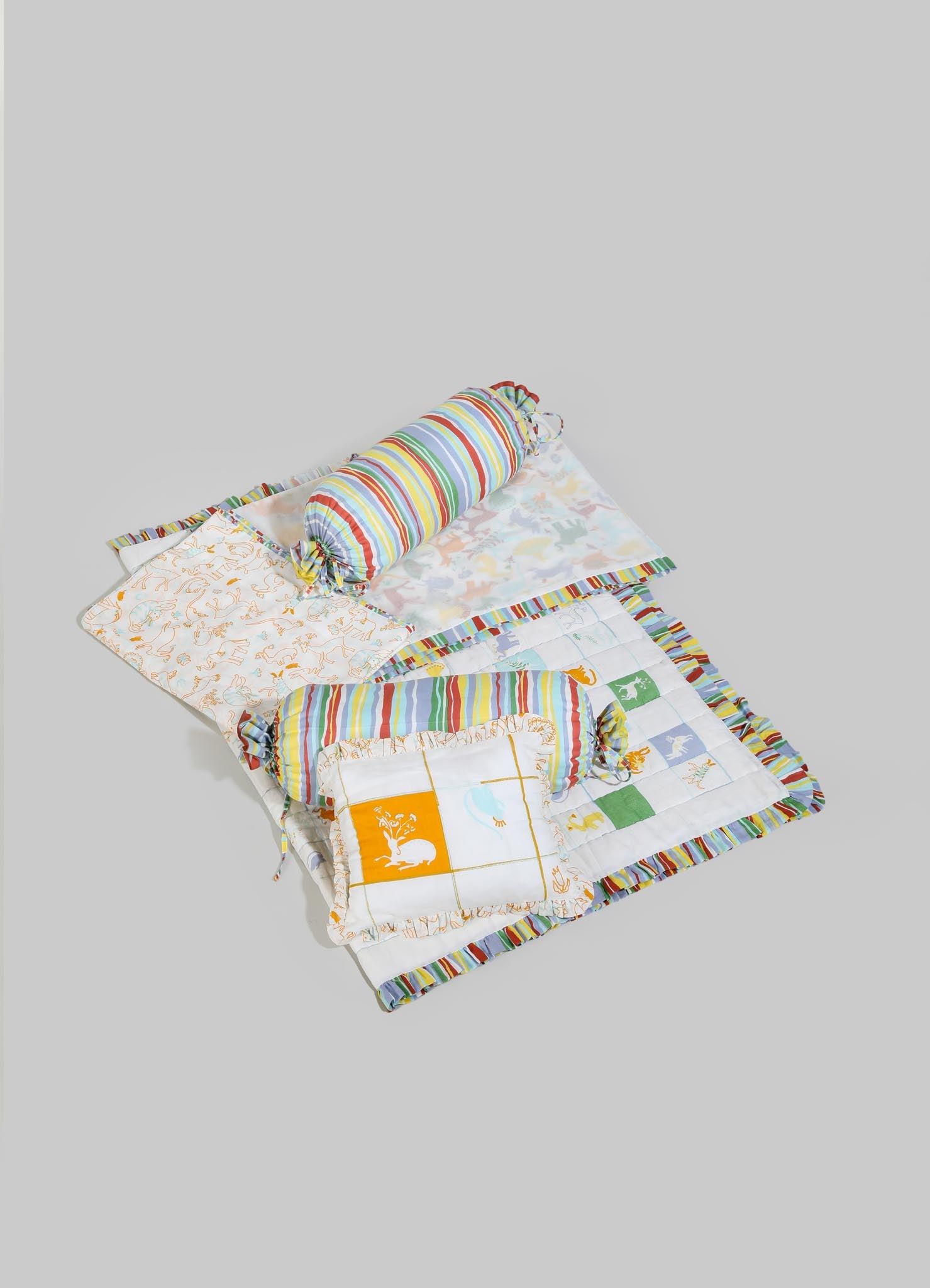 Children's bedding set with animal and floral prints, including a quilt, pillowcases, and a cylindrical bolster, made of cotton fabric with colorful striped and patterned designs.