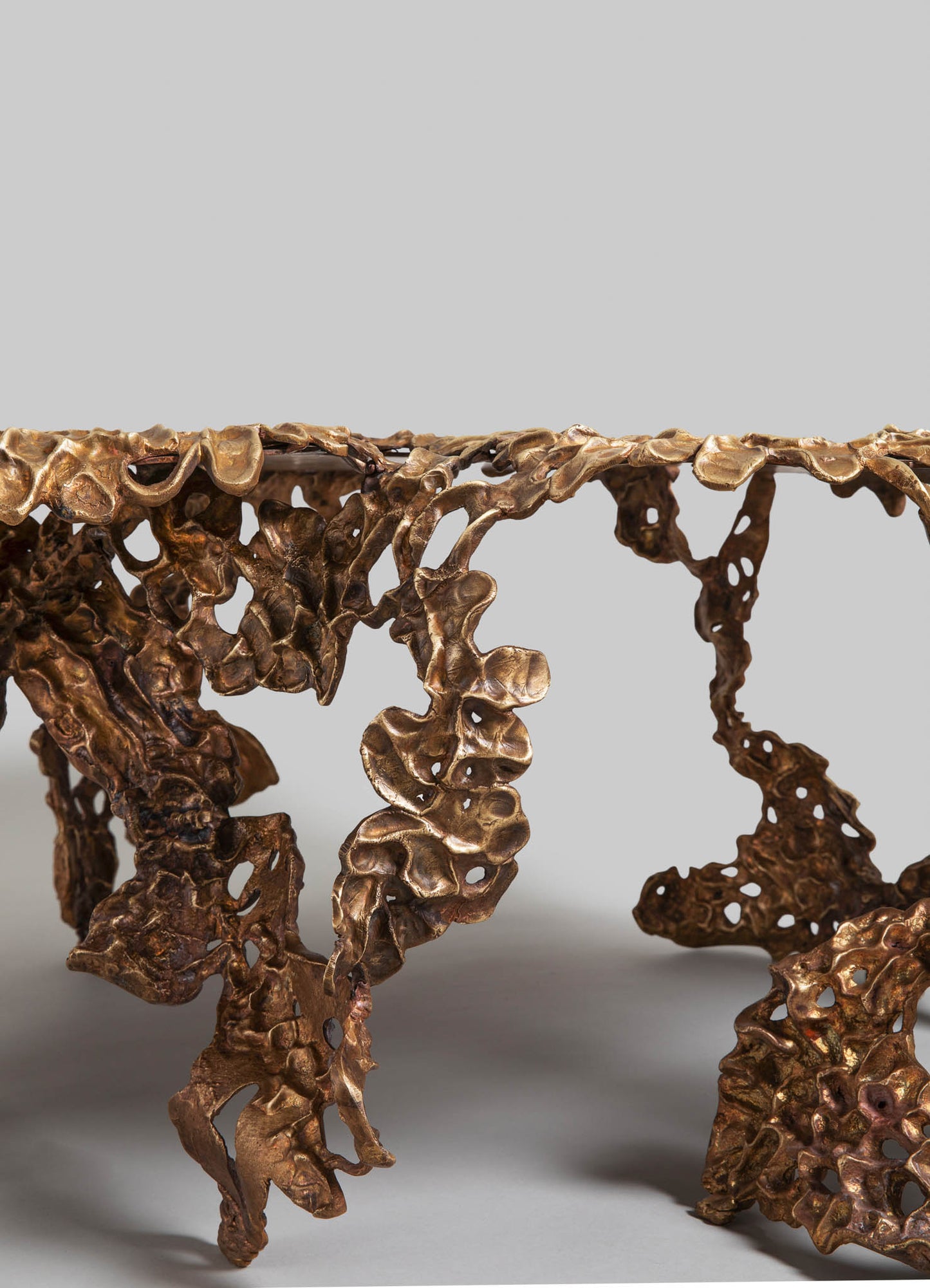 A bronze sculpture or decorative object featuring an organic, irregular shape with a textured, hole-filled surface, resembling natural forms or coral motifs.