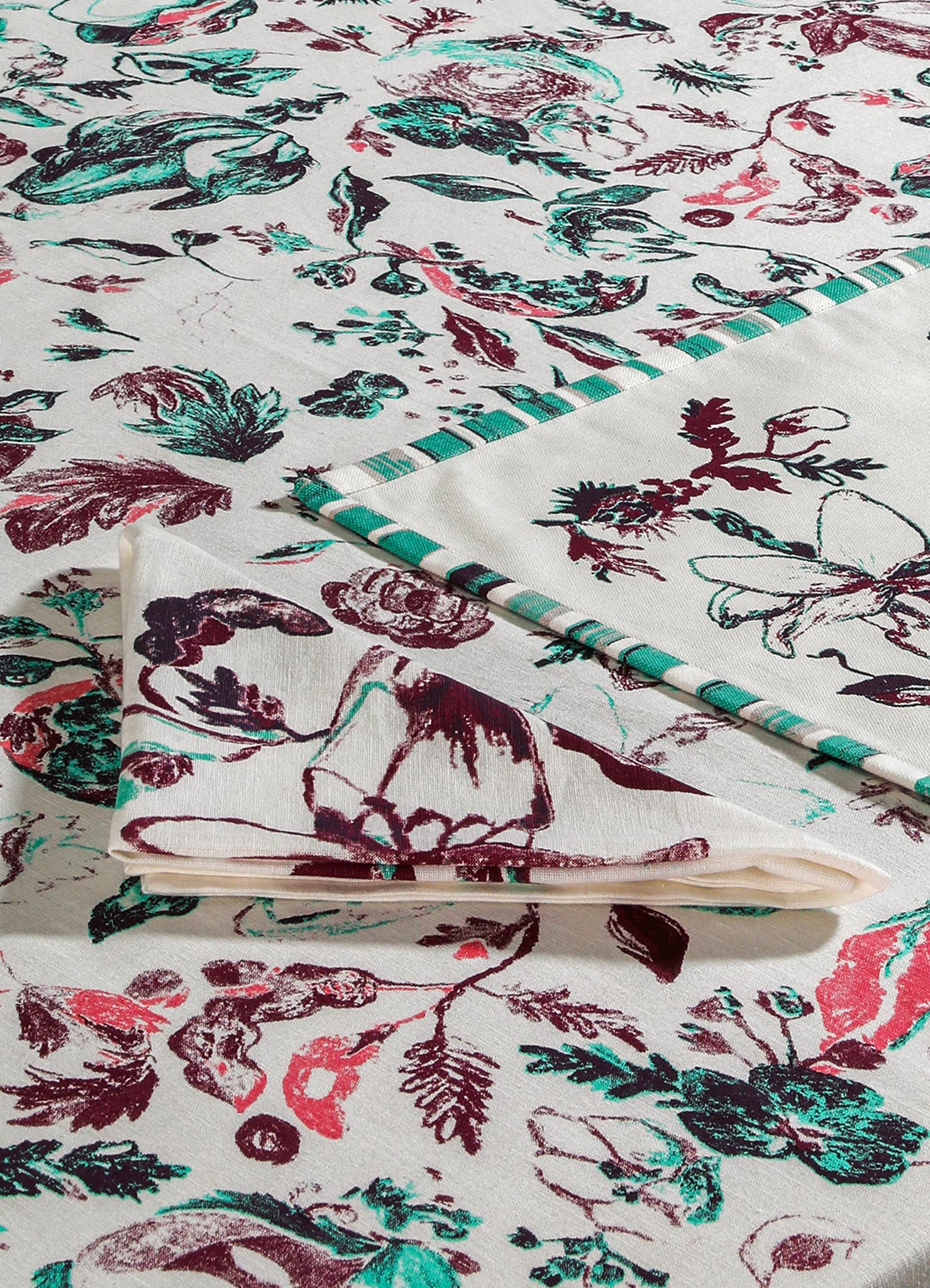 Printed cotton table linen set featuring floral and butterfly motifs in shades of burgundy, teal, and beige. The fabric displays a contemporary design with vibrant botanical patterns.