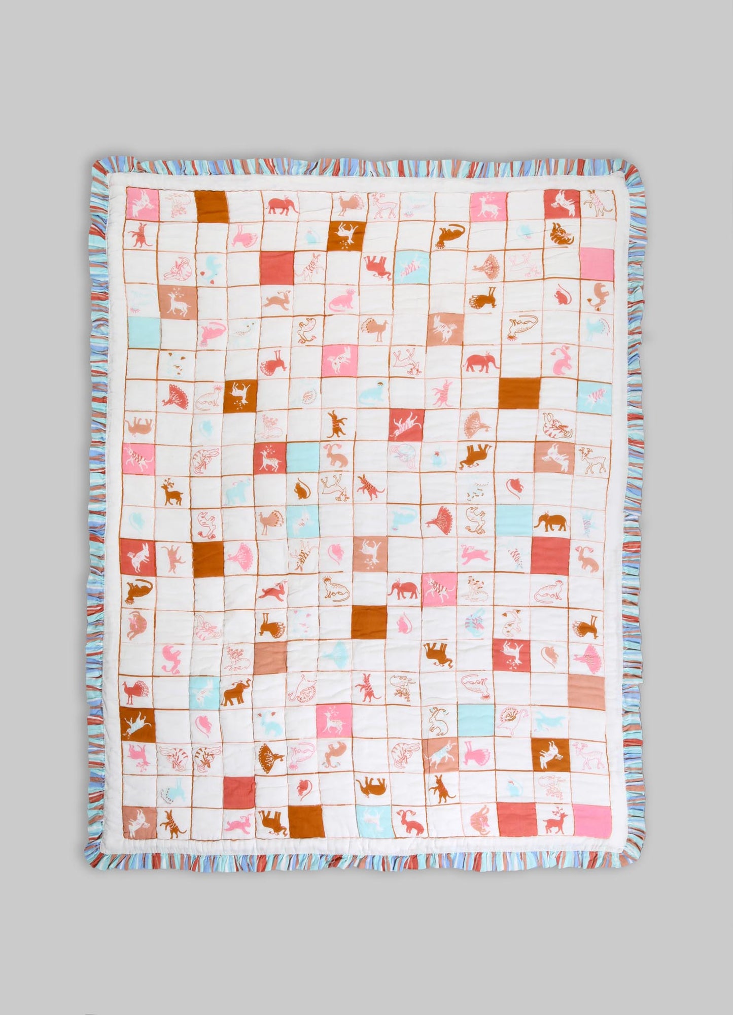 Quilt made of soft cotton fabric featuring a playful animal motif with pink, orange, and light blue colors, bordered with a ruffled striped trim in similar pastel tones.