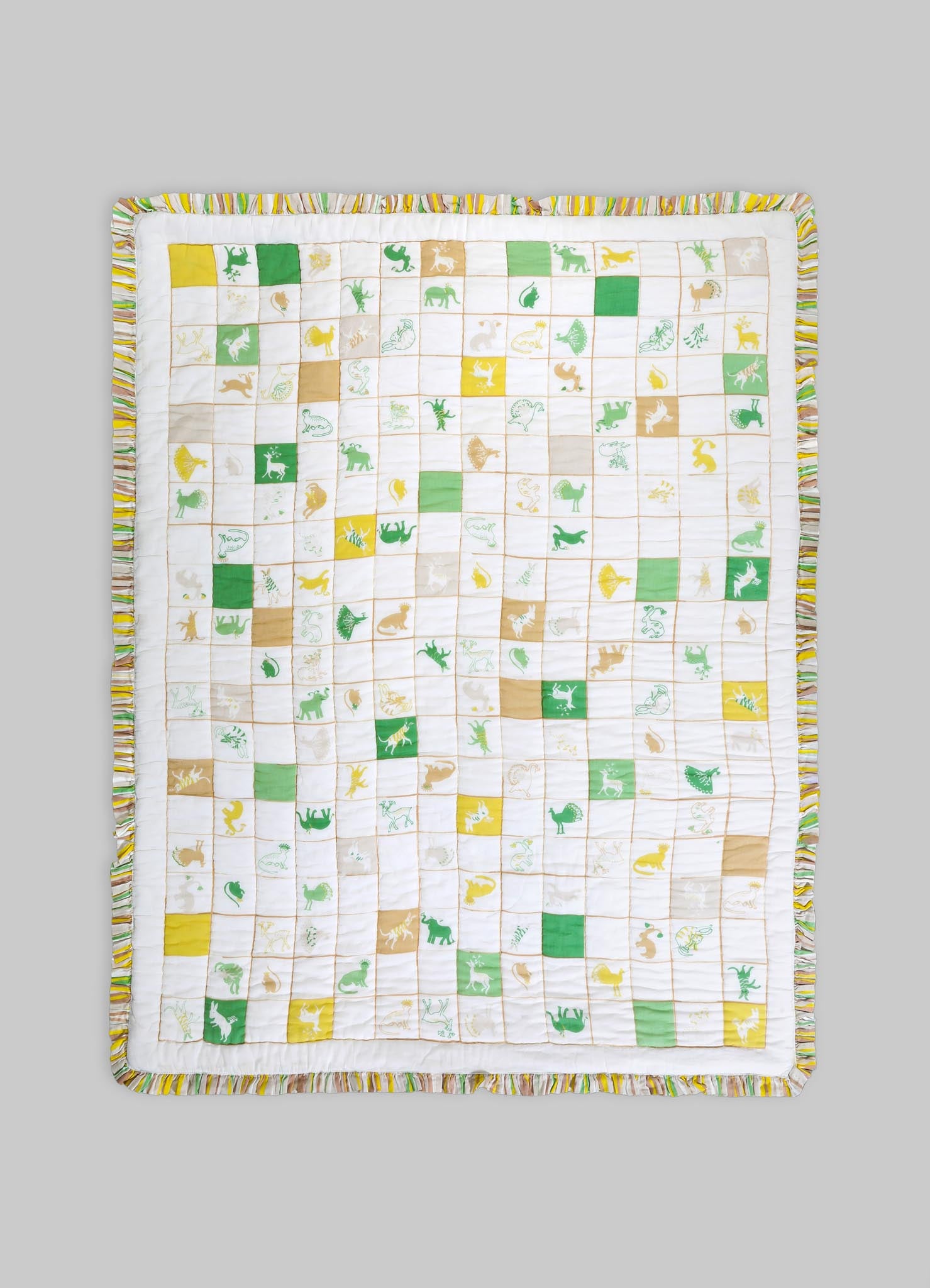 A quilt with a playful animal motif in green, yellow, and beige tones, featuring embroidered and printed animal illustrations within a grid pattern. The quilt has a fabric border with multicolored stripes.
