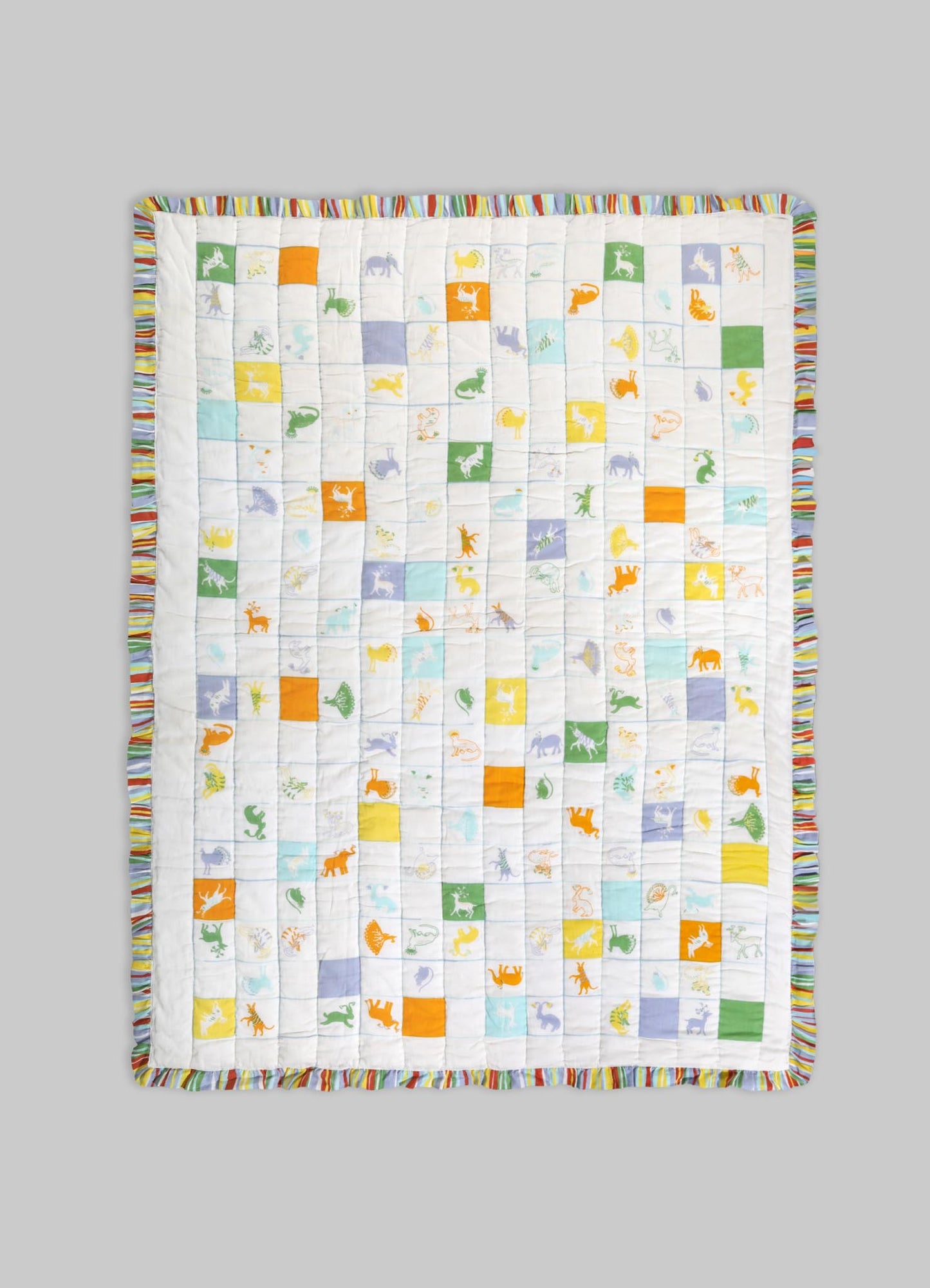 Quilt with colorful animal motifs and geometric patches on a white background, edged with a striped multicolored border. Made from soft fabric, suitable for children's bedding or playful decor.