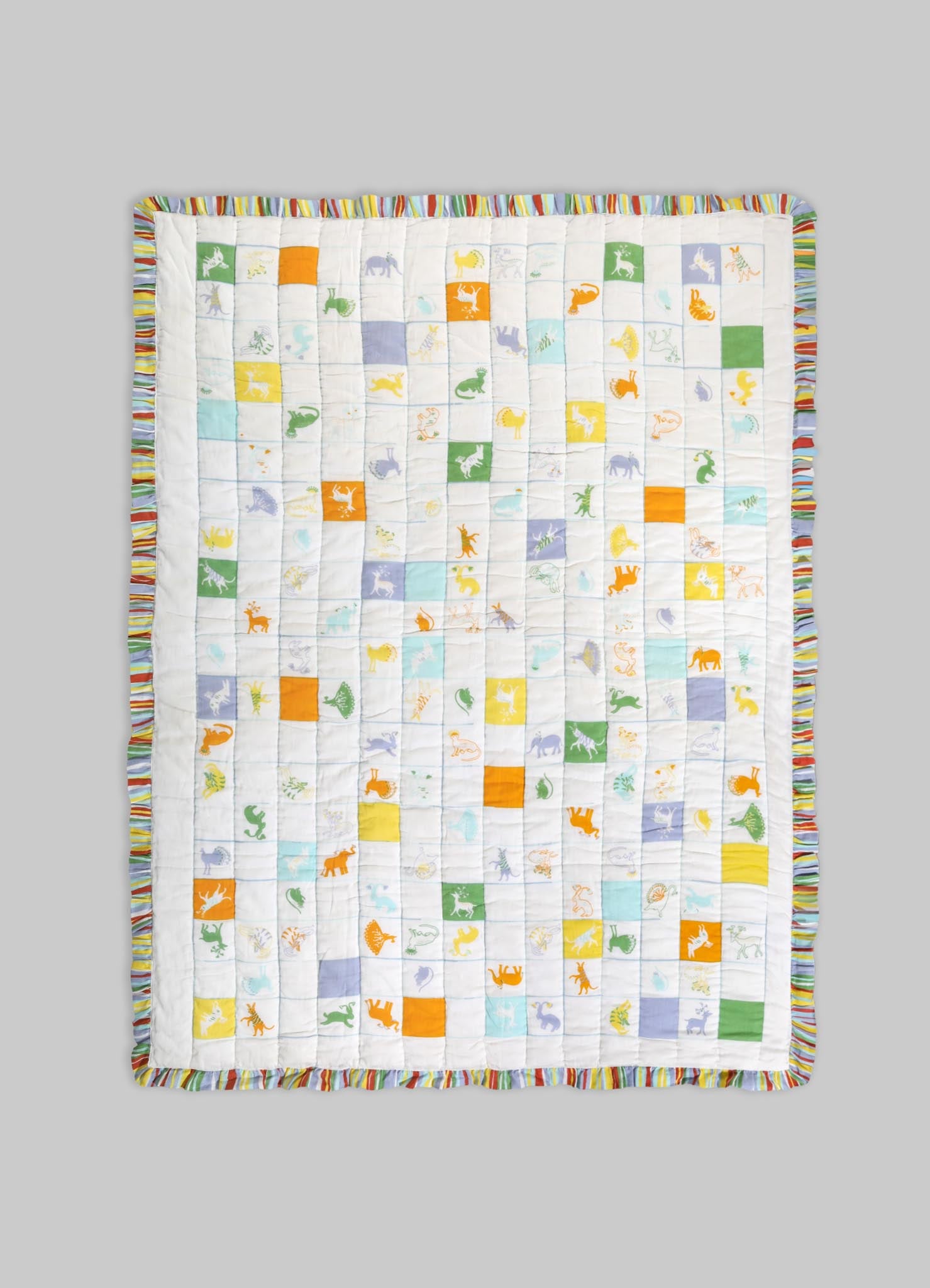 Quilt with colorful animal motifs and geometric patches on a white background, edged with a striped multicolored border. Made from soft fabric, suitable for children's bedding or playful decor.