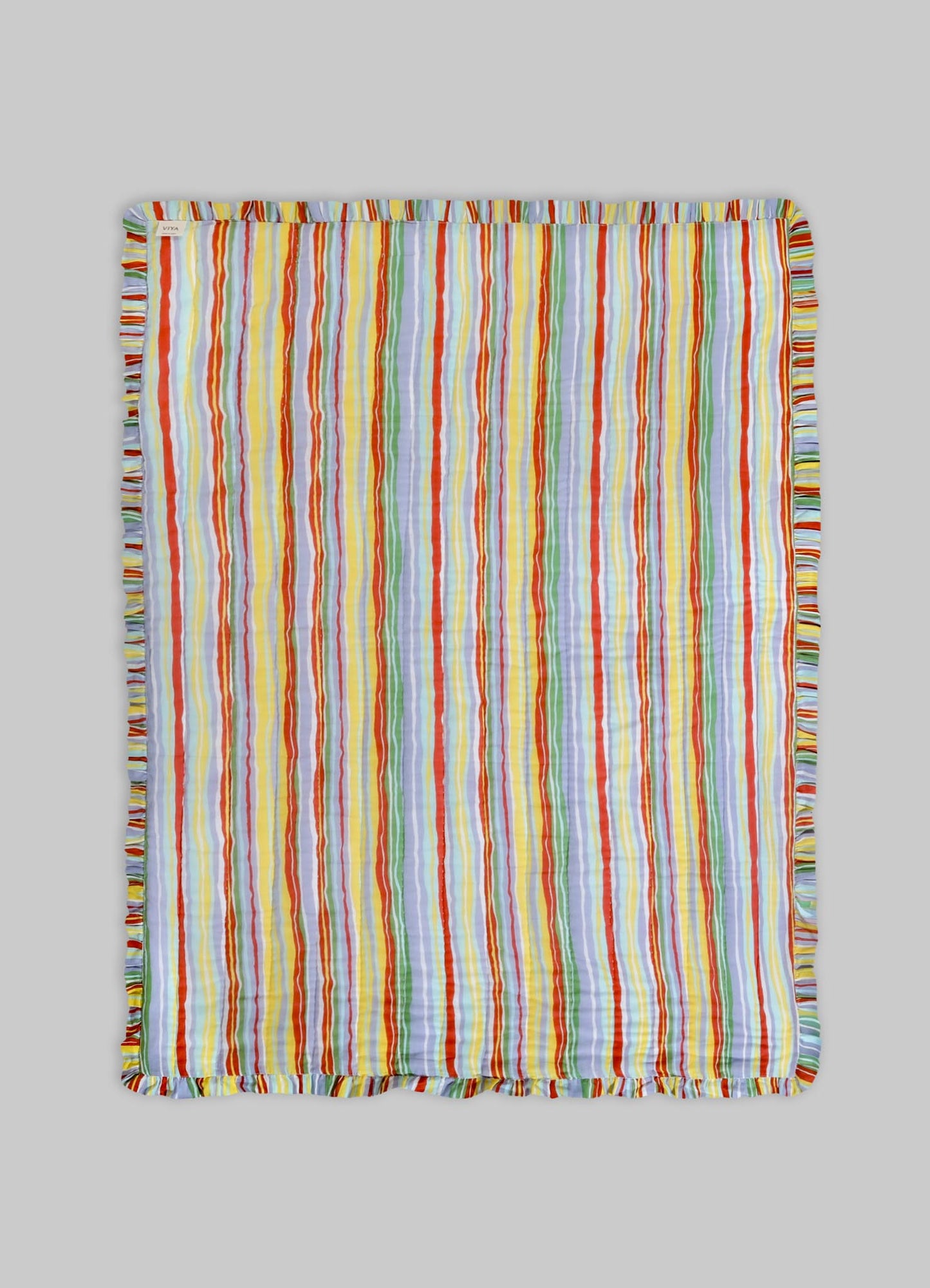A woven textile or blanket featuring multicolored vertical stripes in shades of red, yellow, orange, green, blue, and purple, finished with a ruffled edge slash border.