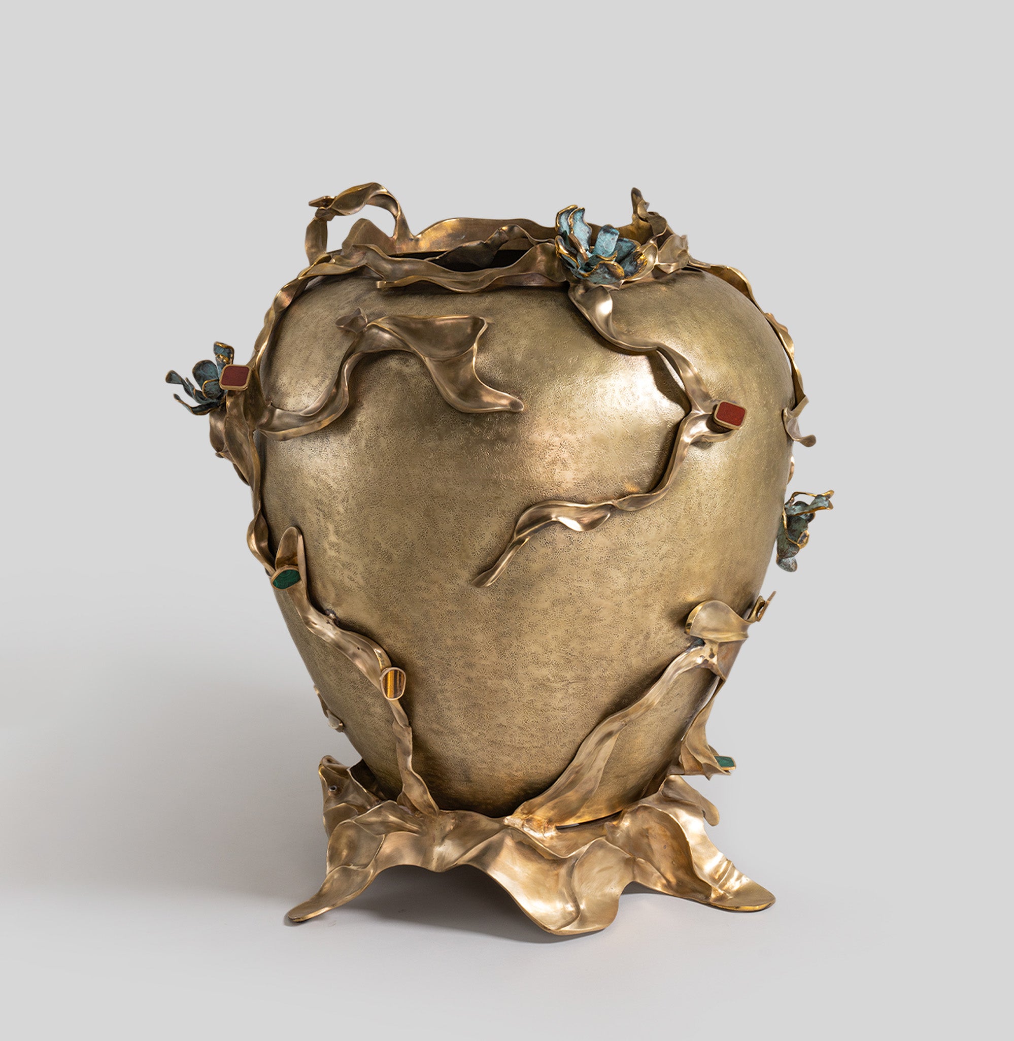 A decorative vase crafted from metal with a textured matte finish, featuring organic, twisting floral motifs in bronze tones with colored accents.
