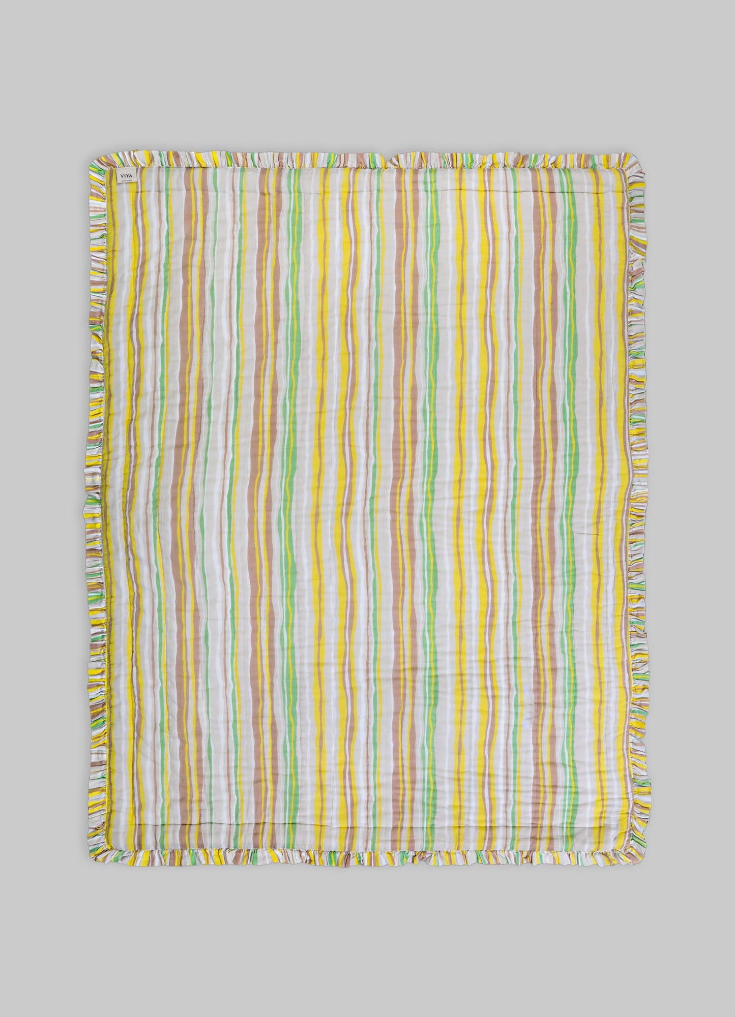 Striped cotton blanket with multicolored vertical lines in yellow, green, white, and beige, finished with a ruffled edge.