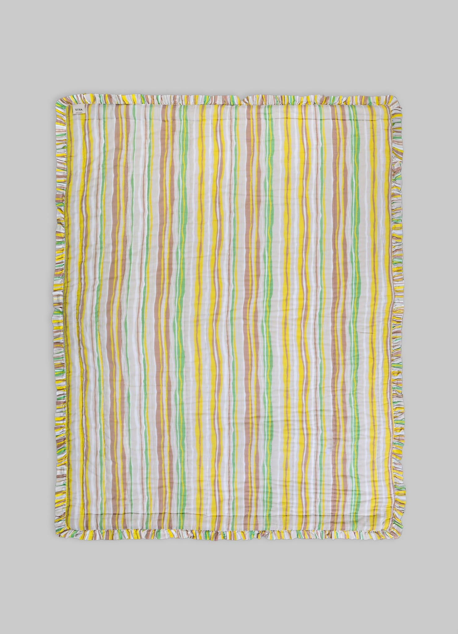 Striped cotton blanket with multicolored vertical lines in yellow, green, white, and beige, finished with a ruffled edge.