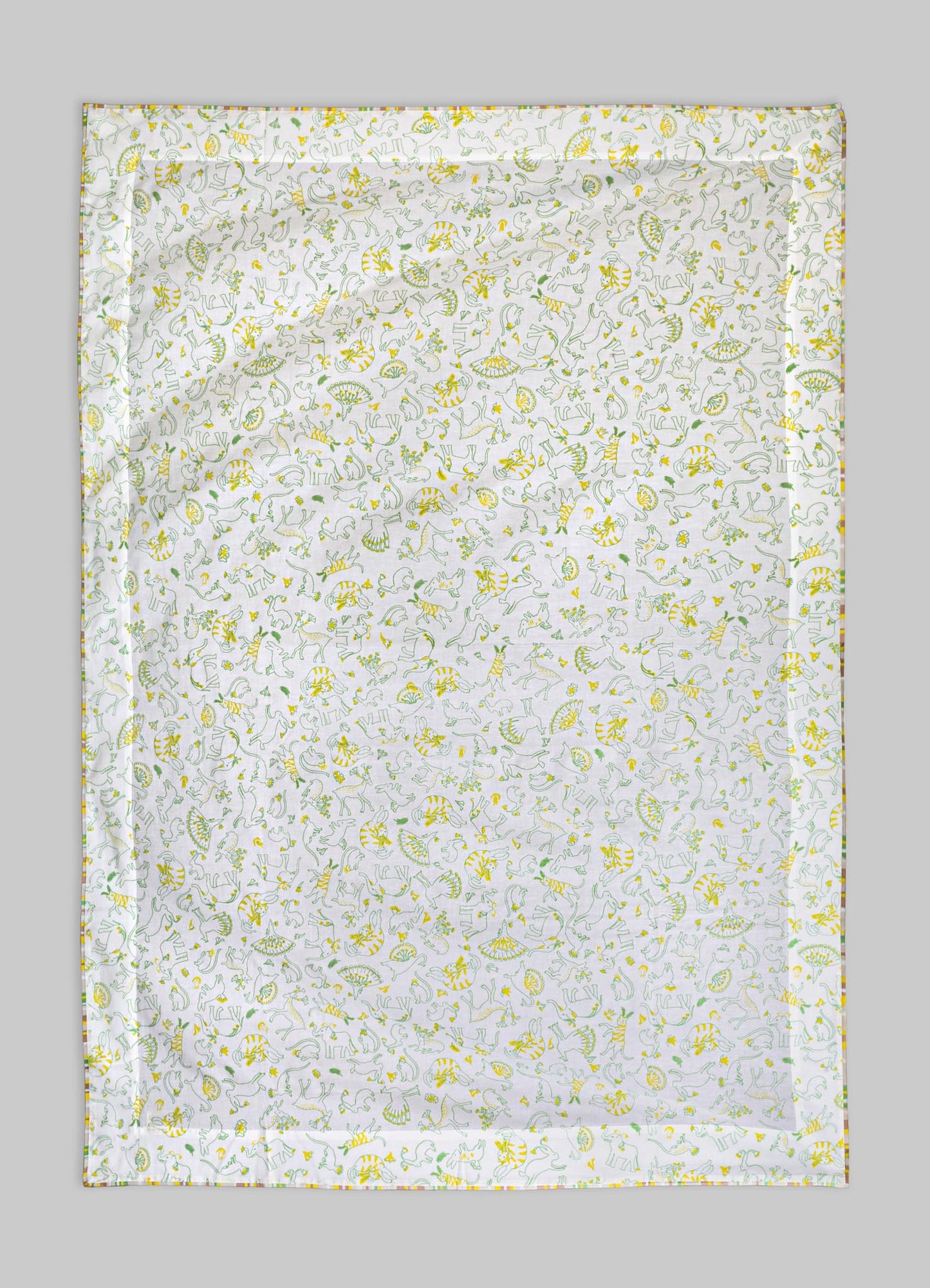 Cotton bed linen or blanket with a playful dinosaur pattern in yellow and green tones, featuring various dinosaurs and foliage motifs on a white background. The fabric has a smooth texture and is edged with a multicolored stitched border, in a casual and whimsical style.